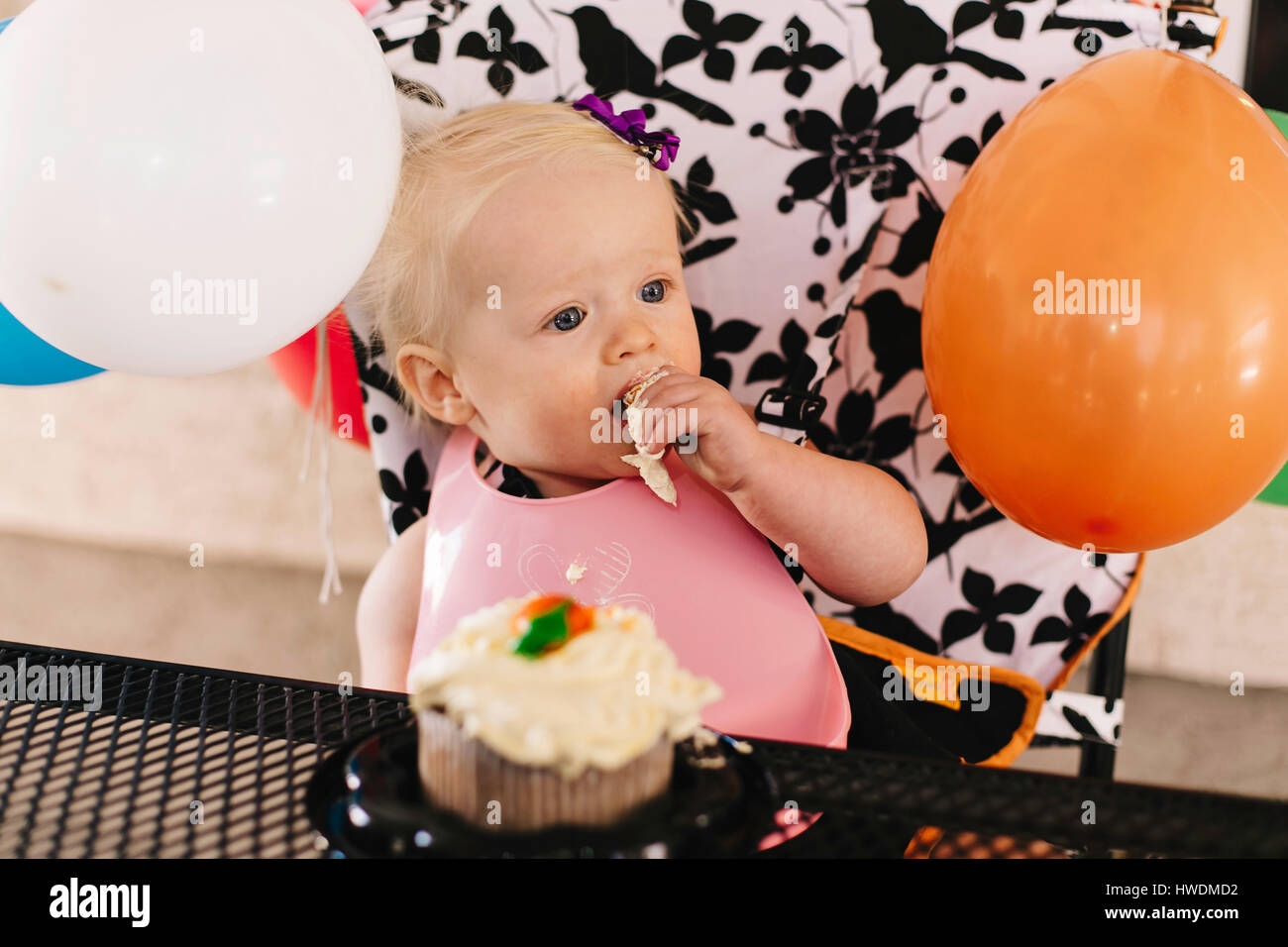Baby Girl sitting in chaise haute, manger du gâteau d'anniversaire Banque D'Images