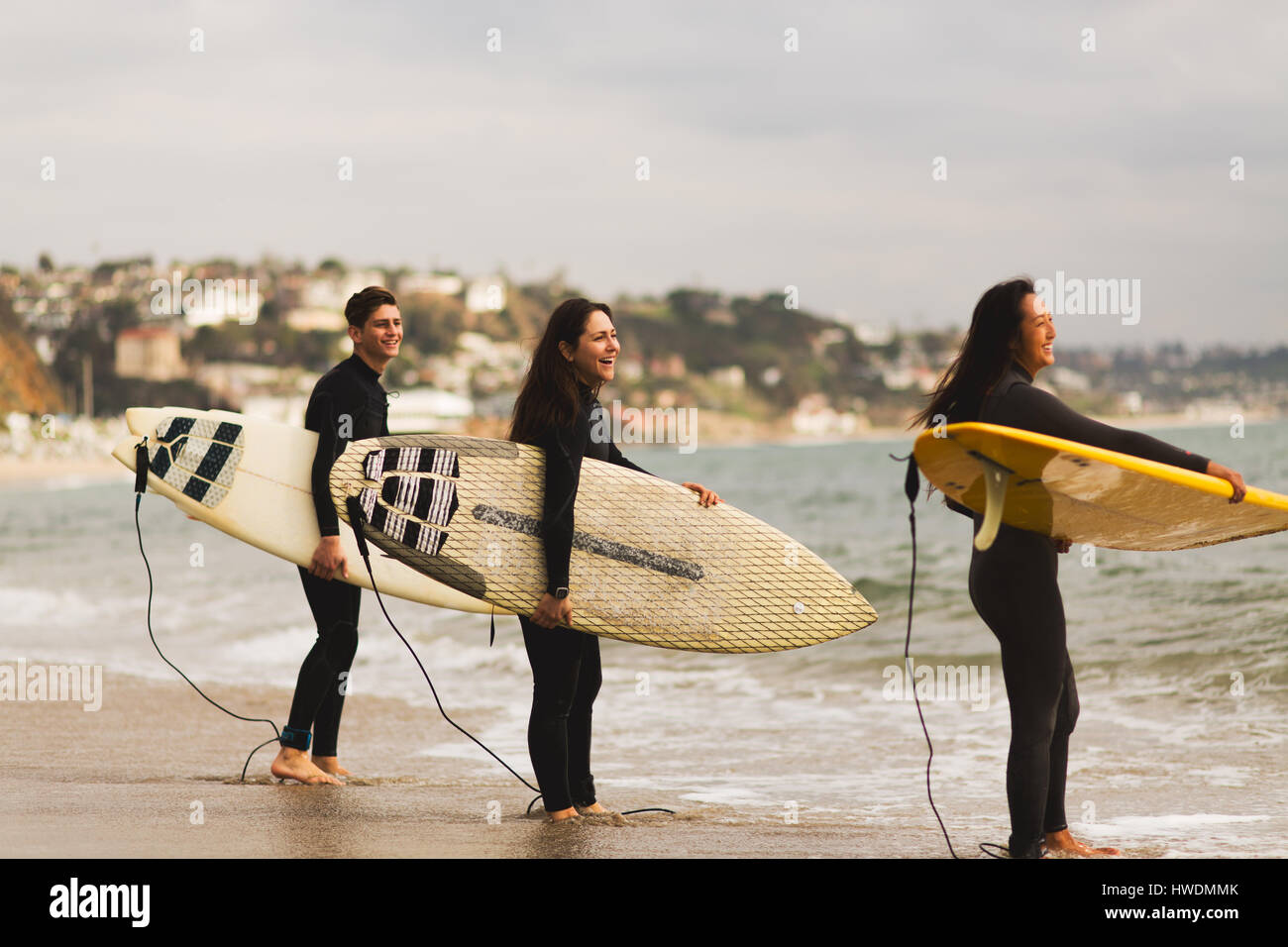 Trois amis debout dans la mer, holding surfboards, préparation pour le surf Banque D'Images