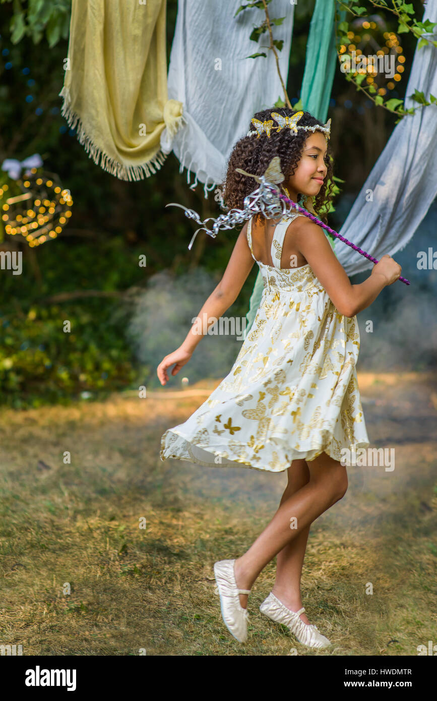 Jeune Fille habillée en fée, holding baguette, jouant à l'extérieur Banque D'Images