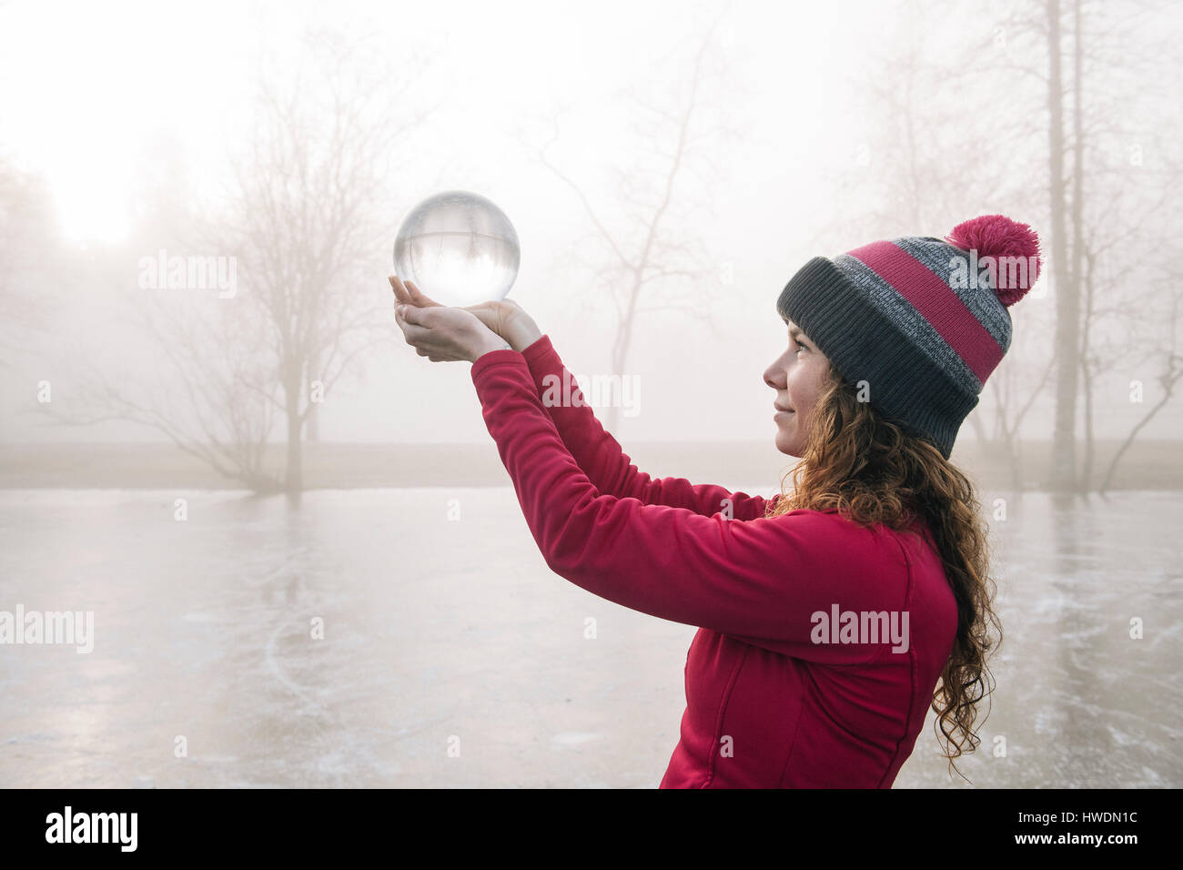 Woman holding up Crystal Ball sur lac gelé Banque D'Images