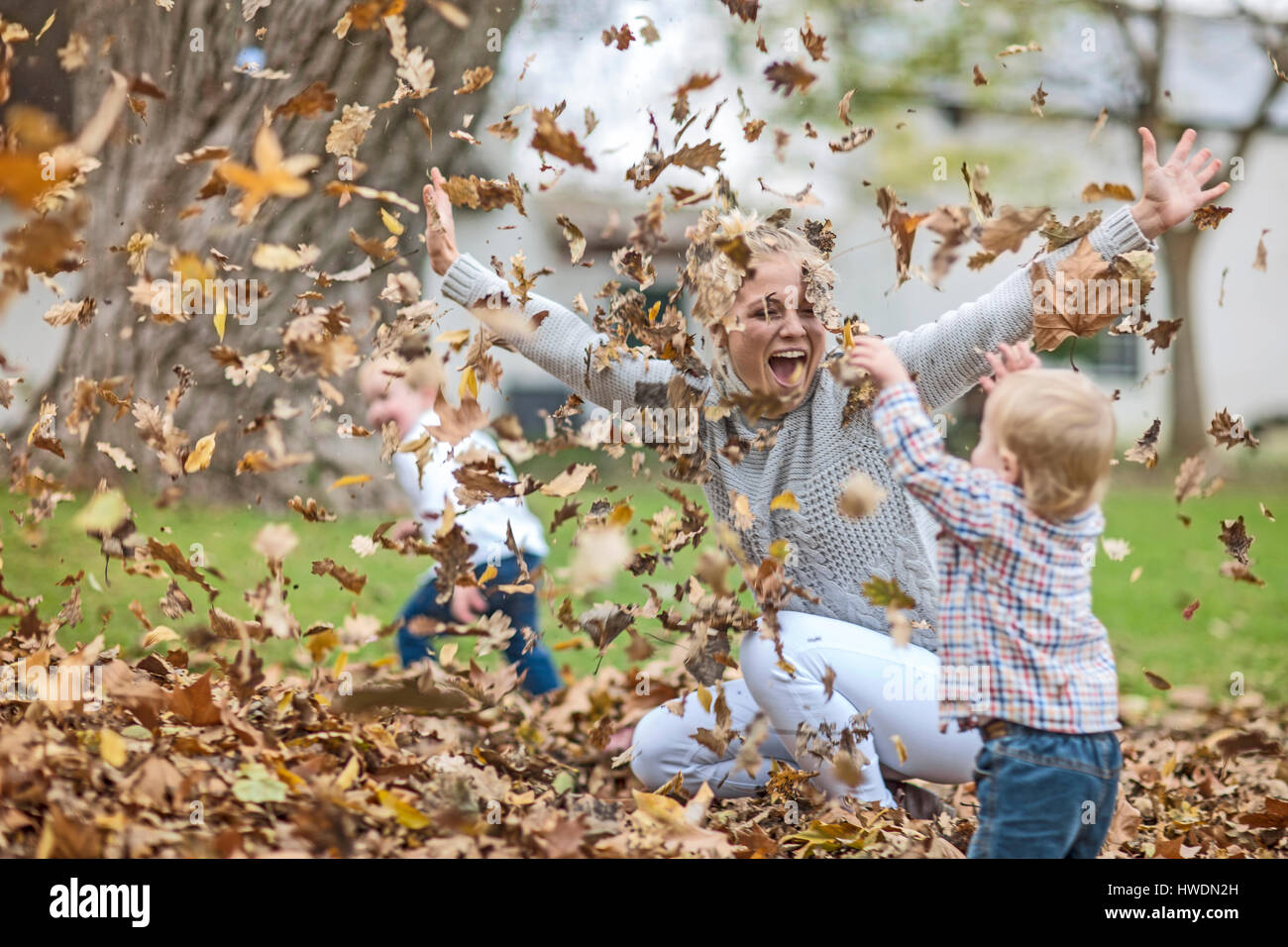 Mère et enfants jouant avec les feuilles tombées Banque D'Images