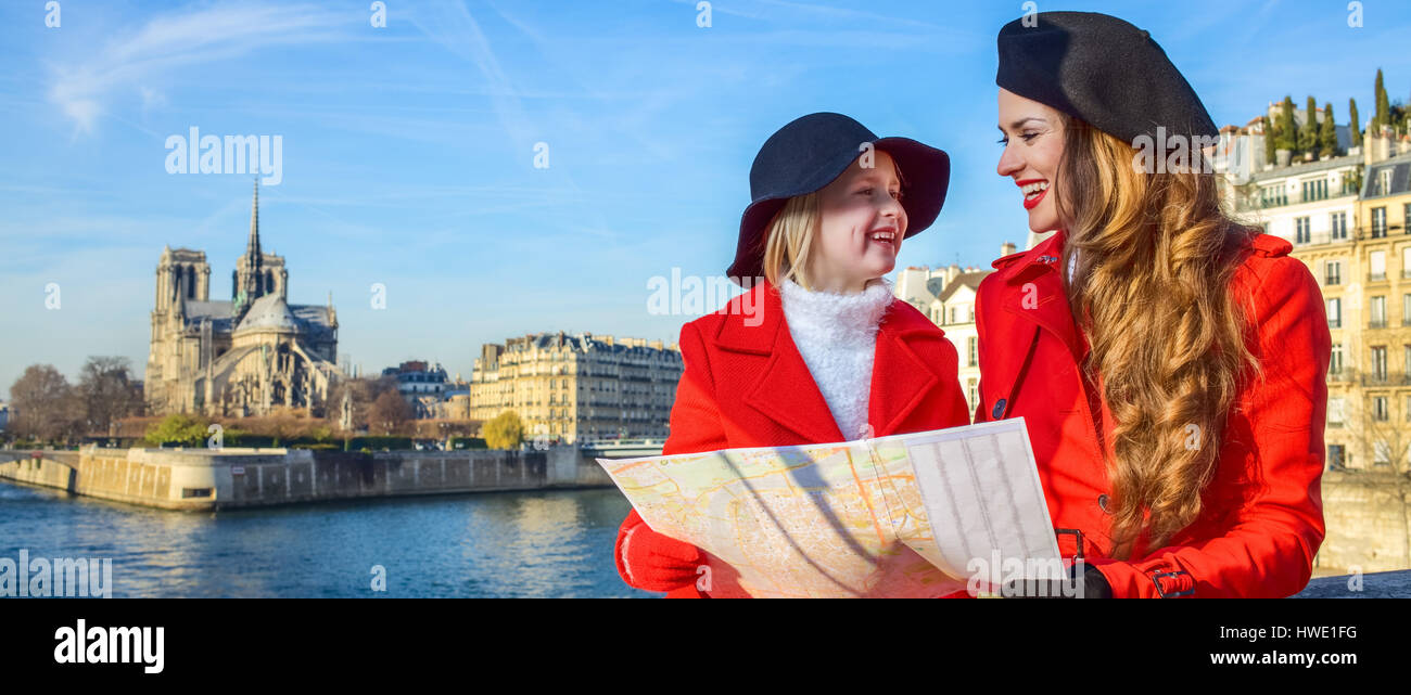 Brillante dans Paris. la mère et la fille à la mode du voyage en tuniques rouges sur le quai près de Notre Dame de Paris à Paris, France avec la carte Banque D'Images