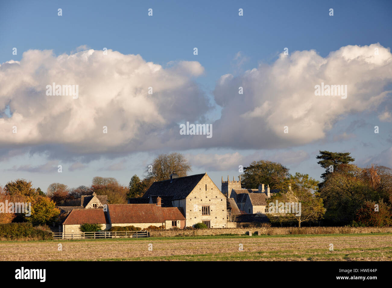 Vue sur les terres agricoles vers le village de Somerford Keynes dans la Loire avec conversion des granges et une tour de l'église Banque D'Images