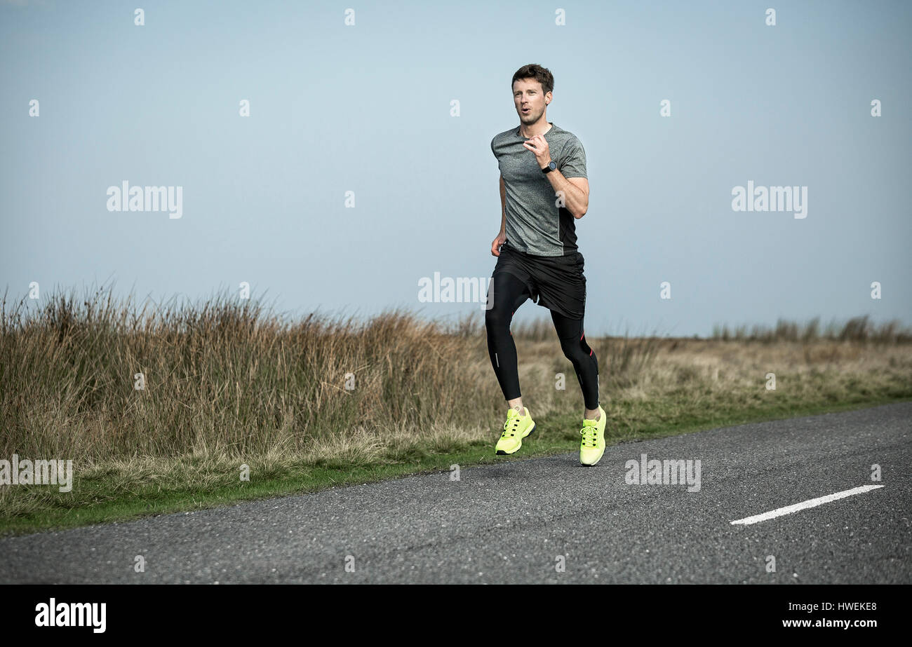 Homme runner le long de la lande rural road Banque D'Images