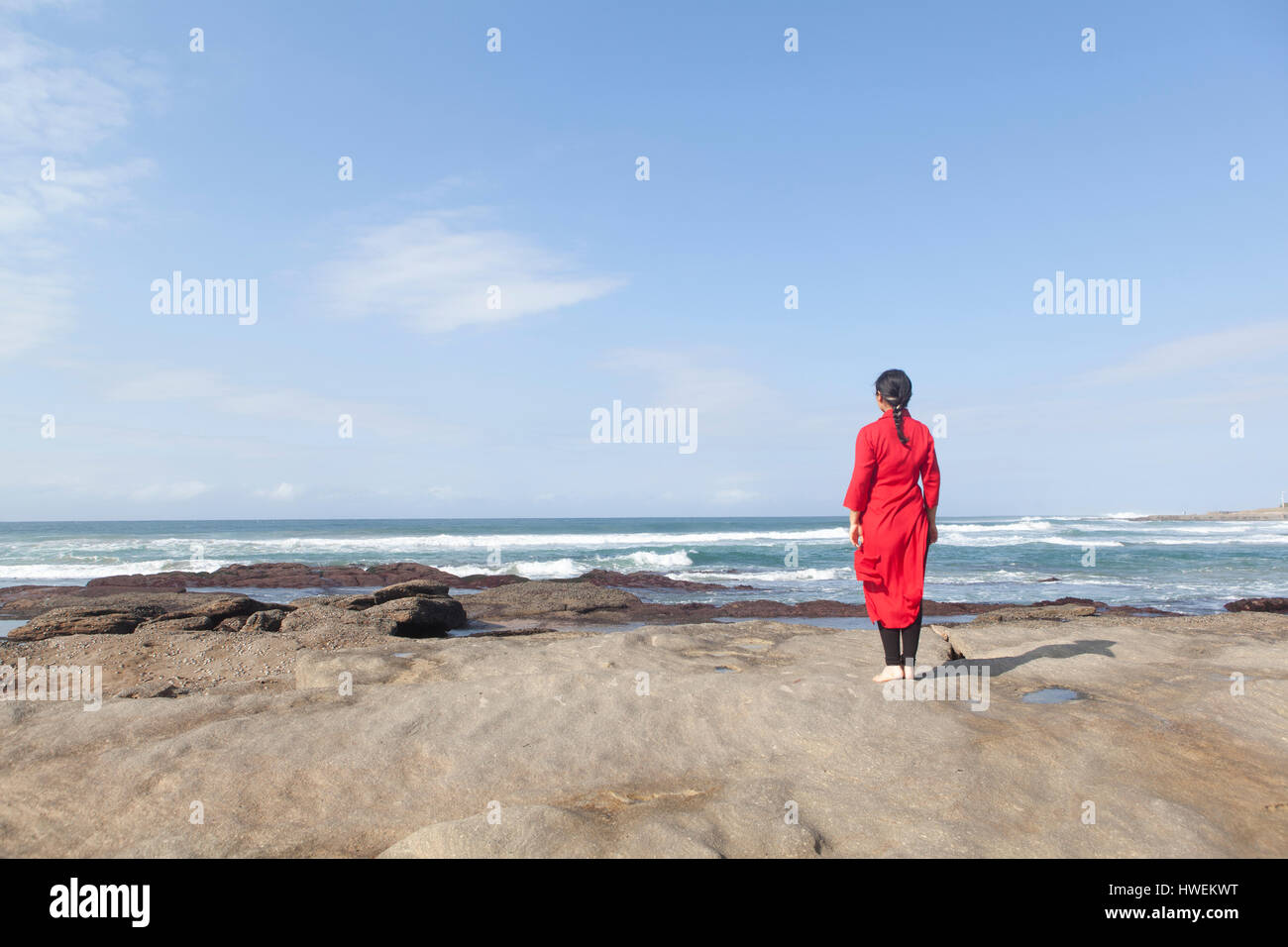 Woman wearing red dress, debout sur les rochers, regardant sur la mer, Afrique du Sud Banque D'Images
