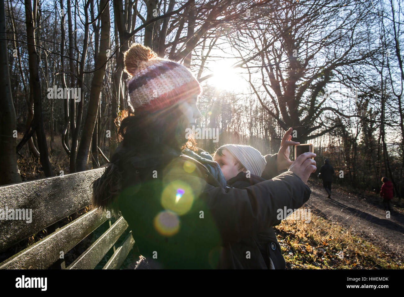 Mère assis sur un banc avec bébé garçon, prenant avec le smartphone selfies Banque D'Images