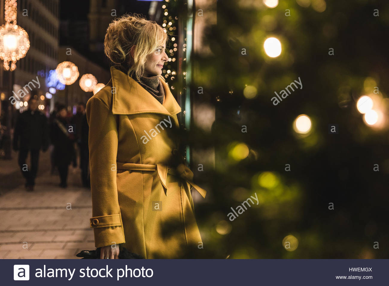 Young woman window shopping de Noël dans la nuit, Munich, Allemagne Banque D'Images