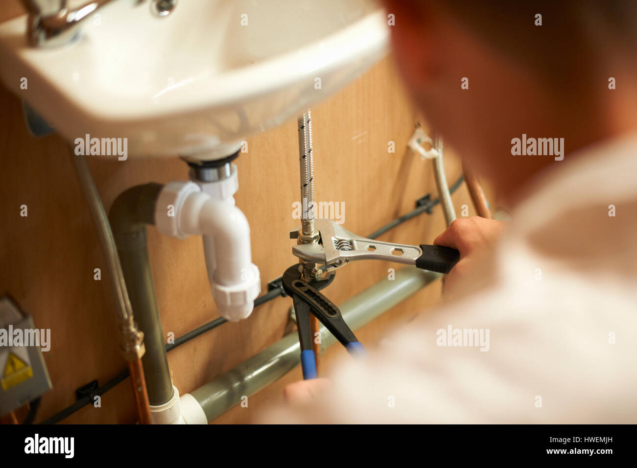 Stagiaire homme clé à molette sur l'aide plombier tuyauterie dans l'atelier du collège Banque D'Images