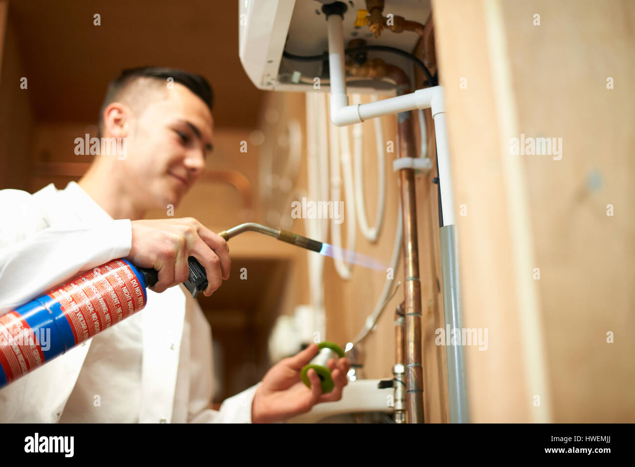 Les jeunes stagiaires à l'aide de mâles plombier chalumeau sur tuyauterie dans l'atelier du collège Banque D'Images