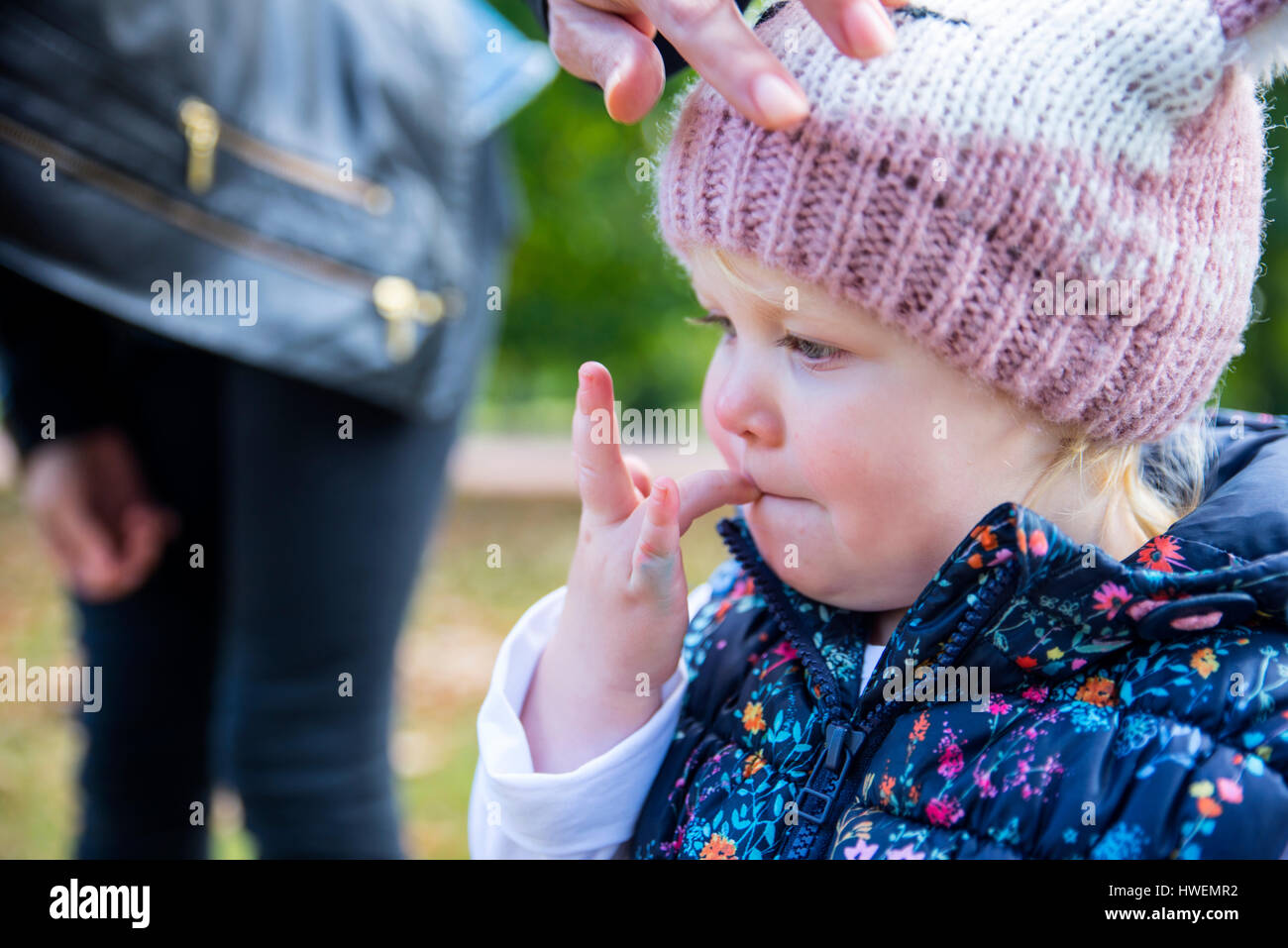 Female toddler avec doigt dans sa bouche en park Banque D'Images