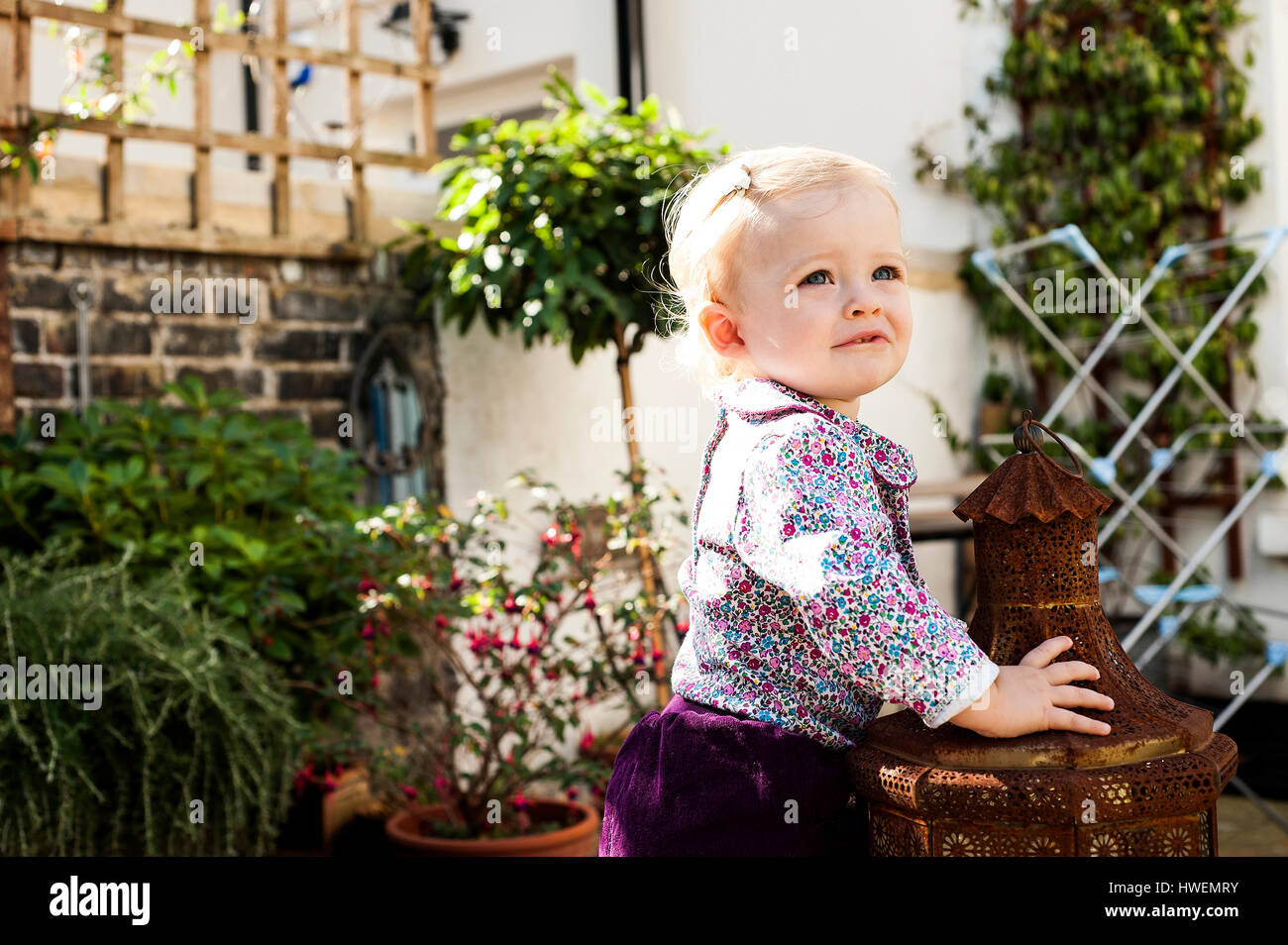 Baby Girl standing tout en se penchant sur la lanterne de jardin Banque D'Images
