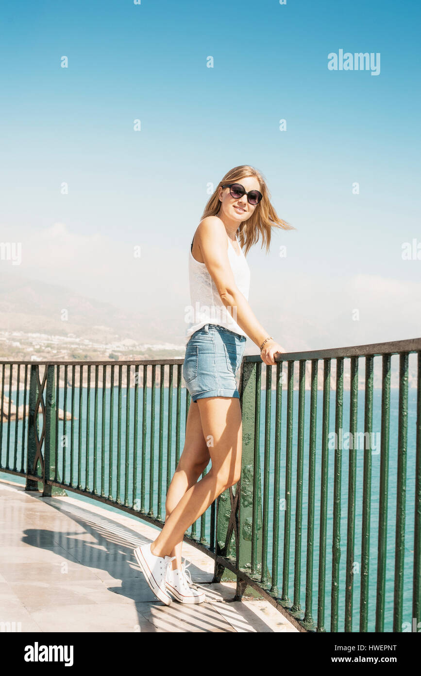 Femme par des garde-corps à la caméra en souriant, Nerja, Espagne Banque D'Images Femme par des garde-corps à la caméra en souriant, Nerja, Espagne Banque D'Images