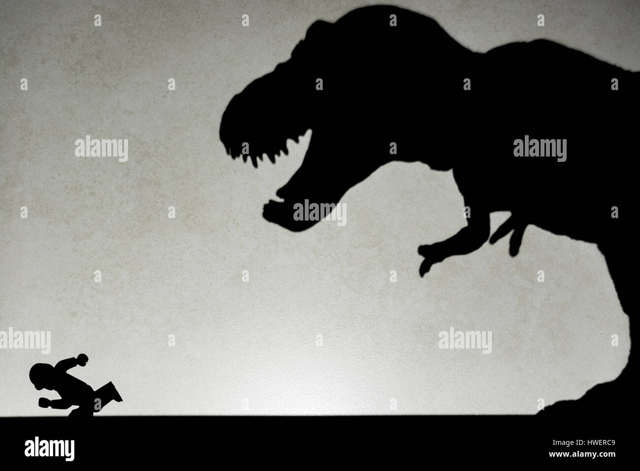 Ombre de tyrannosaurus chasing humain sur mur pas un logo ou d'une marque Banque D'Images