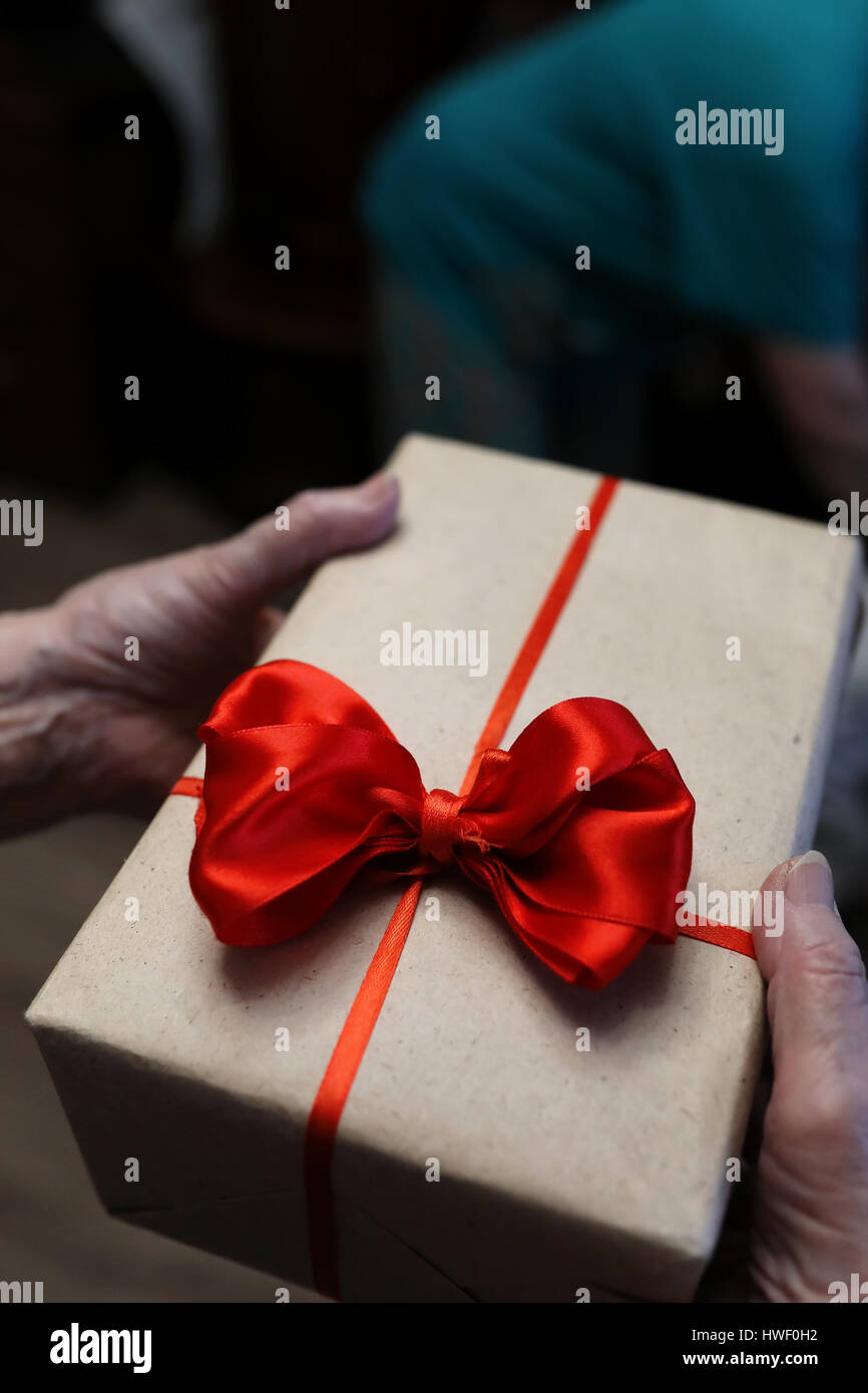 Boîte-cadeau avec arc rouge en grand-mère mains Banque D'Images