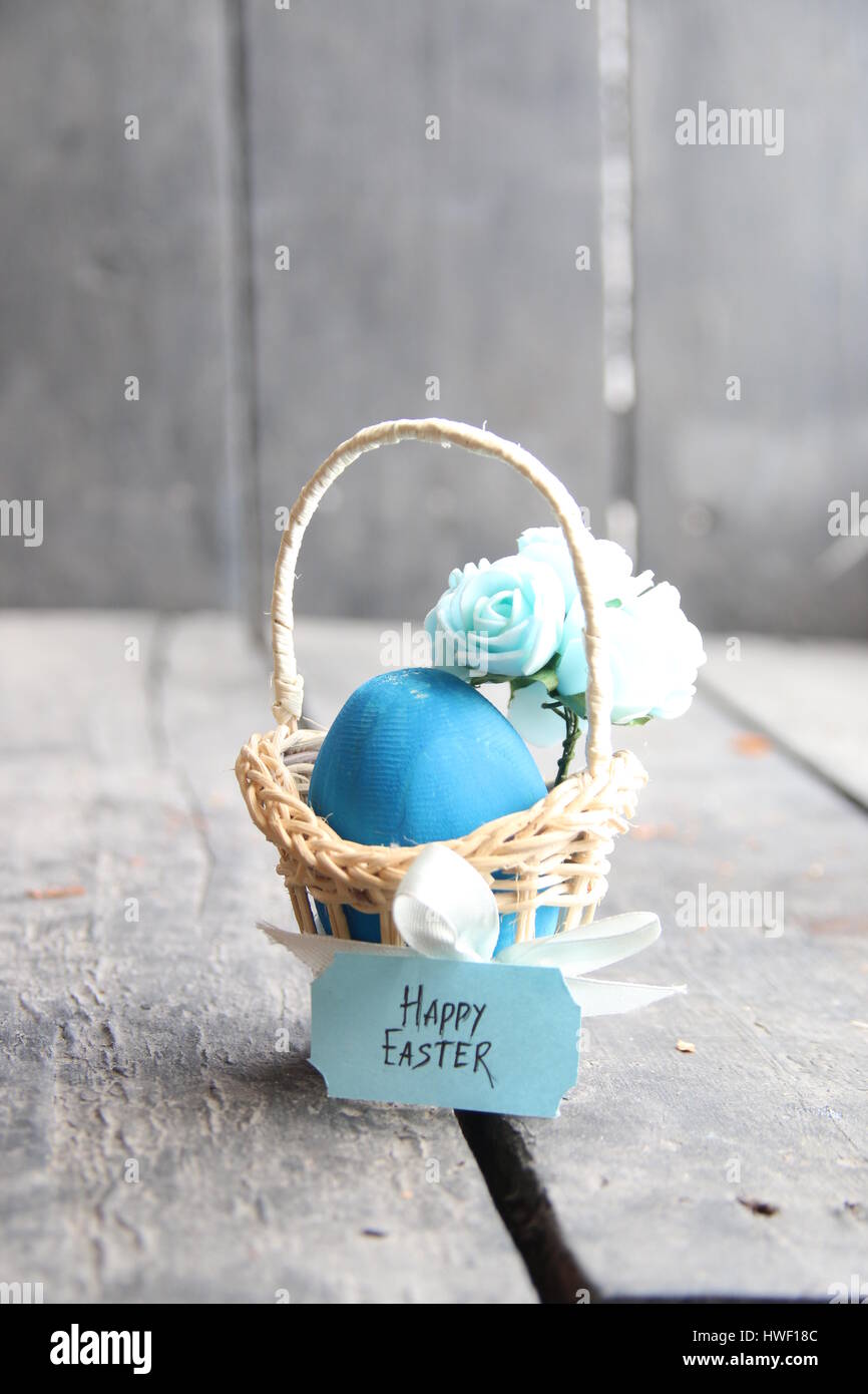 Joyeuses Pâques. Oeuf de Pâques dans un panier sur un arrière-plan vintage et de fleurs de printemps. Banque D'Images