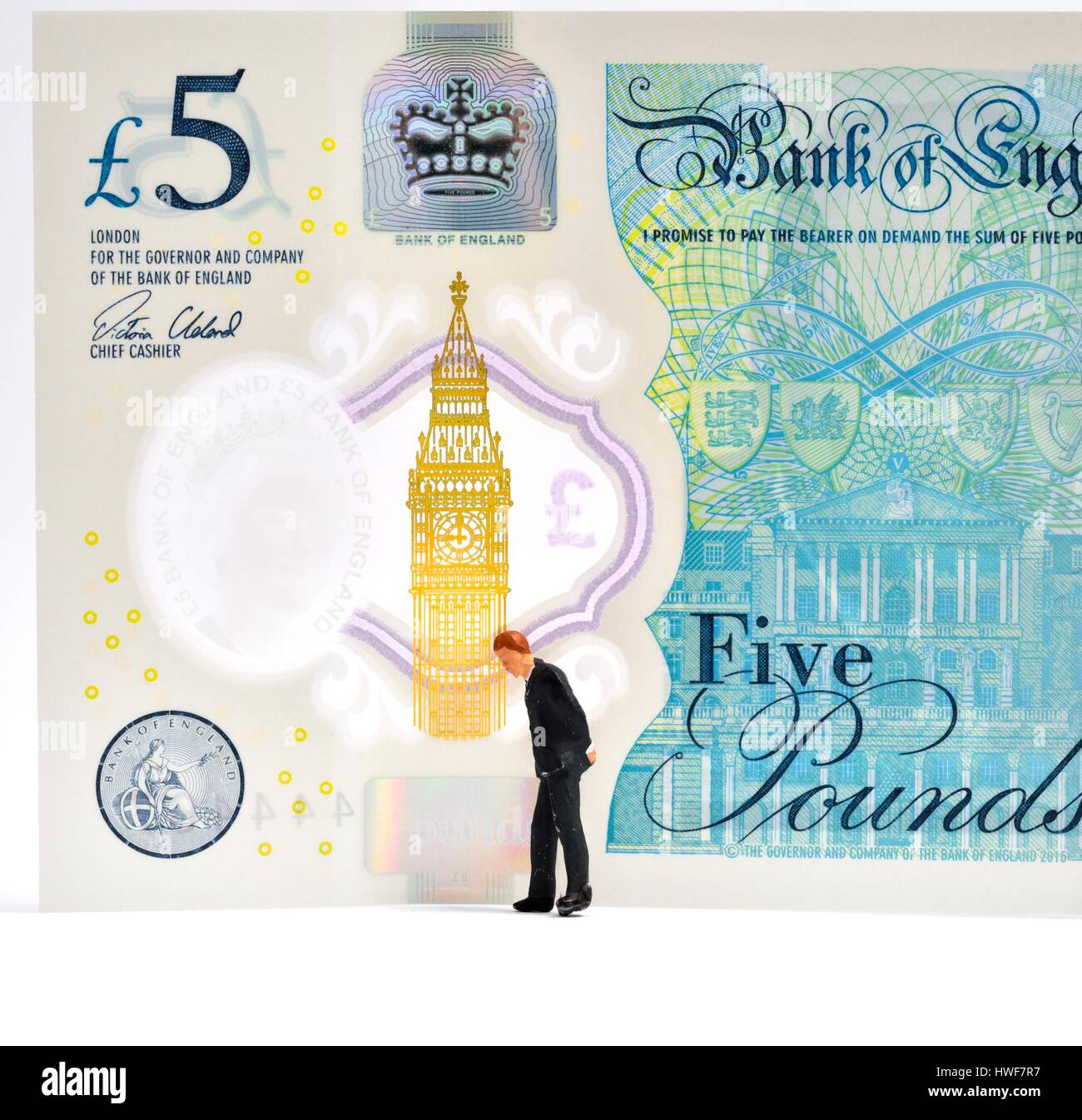 Figurine miniature business man standing in front of a 5 pound note. Banque D'Images