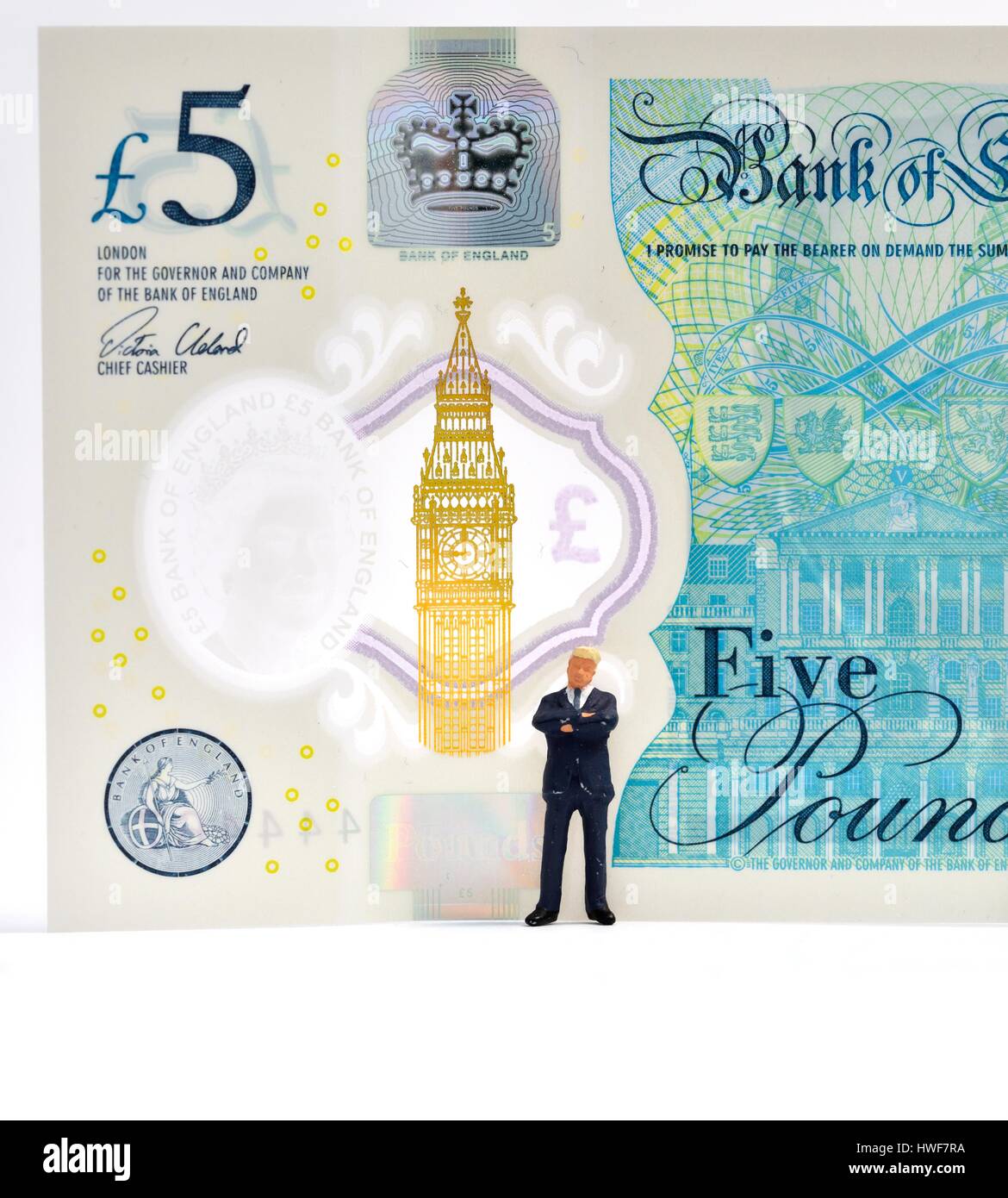 Figurine miniature business man standing in front of a 5 pound note. Banque D'Images