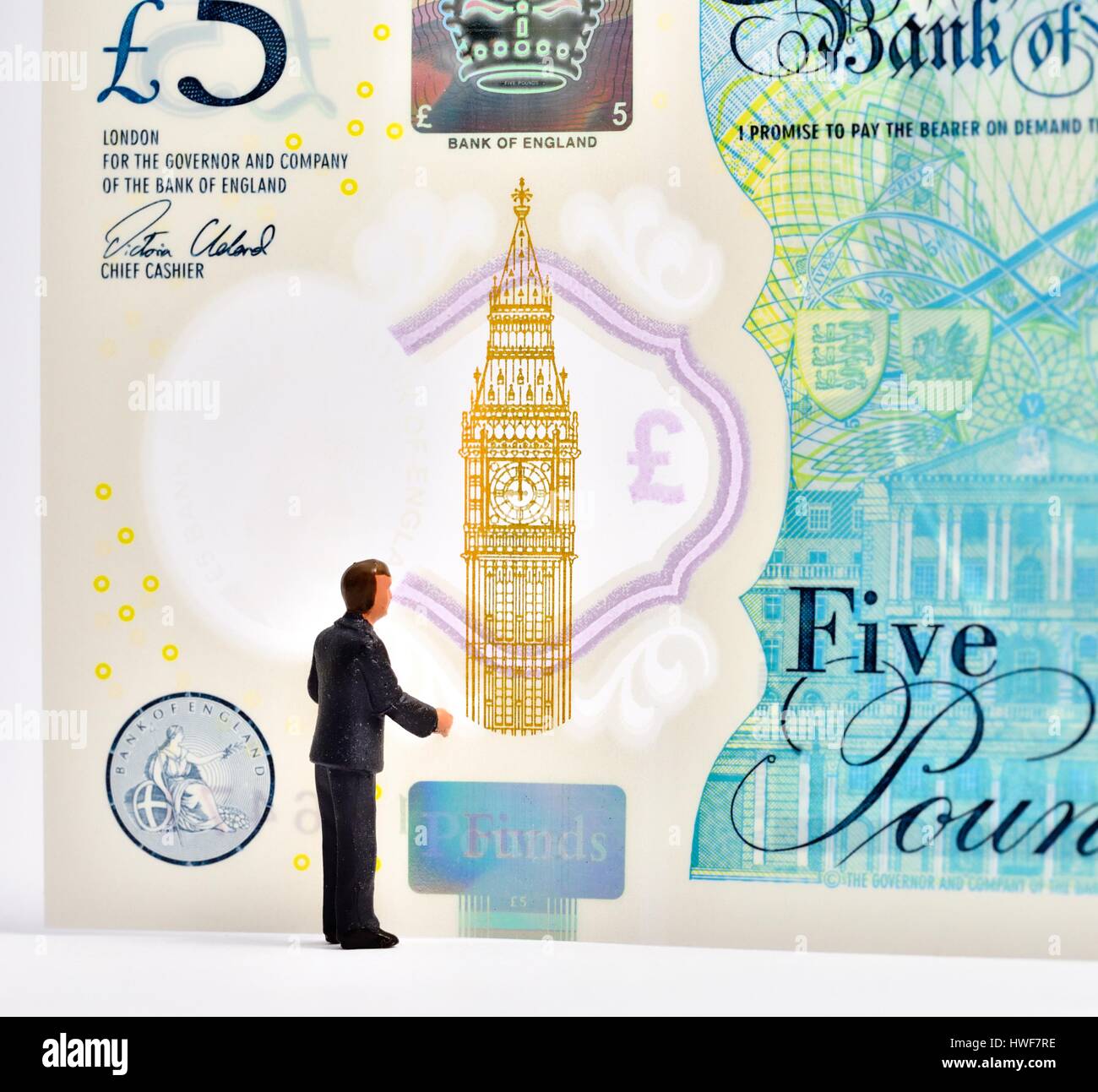 Figurine miniature business man standing in front of a 5 pound note. Banque D'Images
