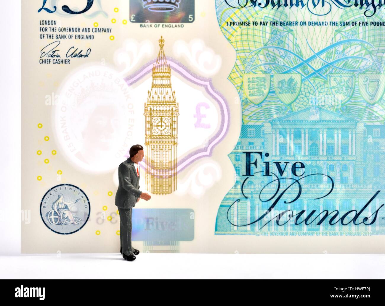 Figurine miniature business man standing in front of a 5 pound note. Banque D'Images