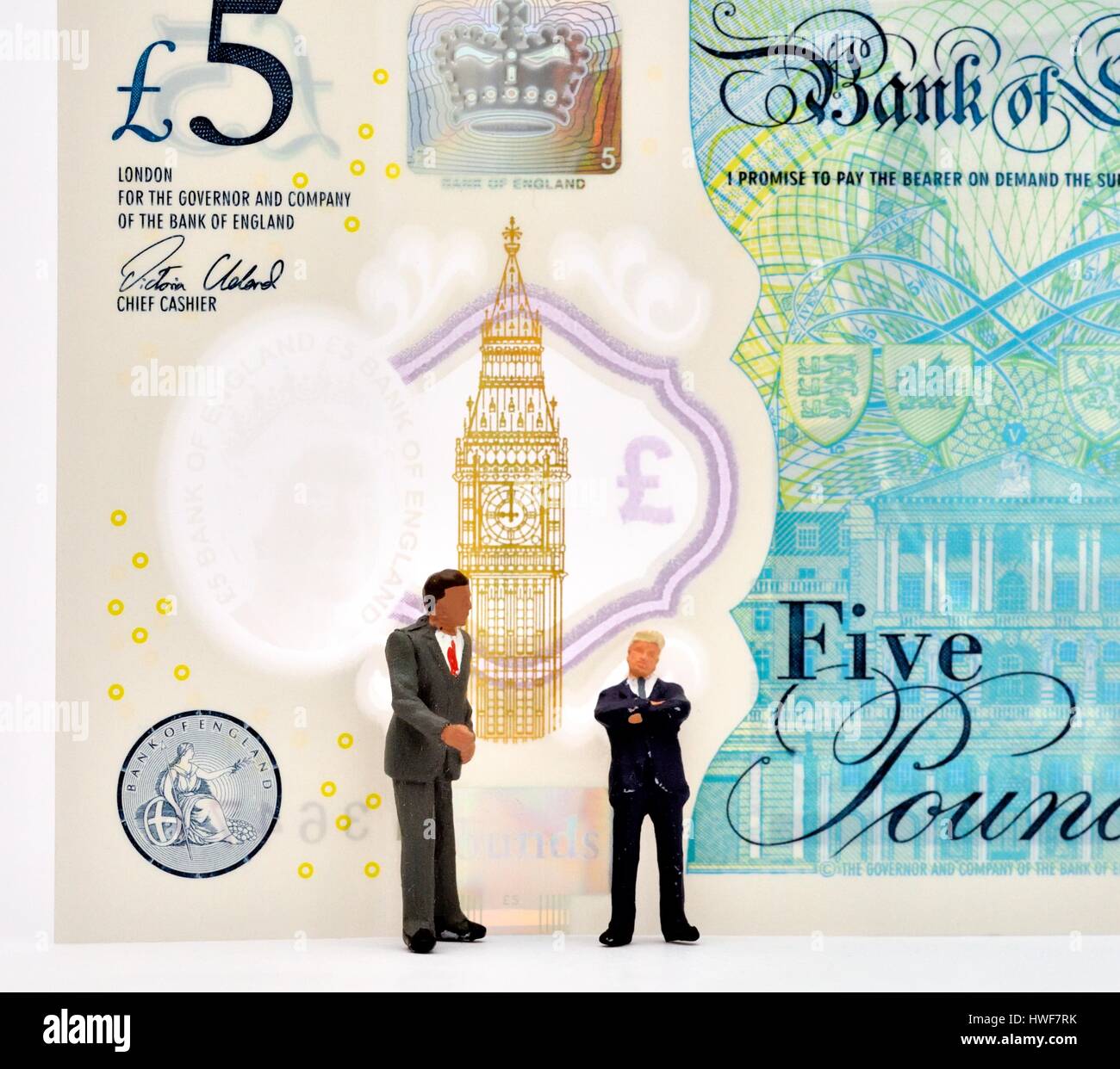 Les hommes d'affaires figurine miniature debout devant une note cinq livres. Banque D'Images