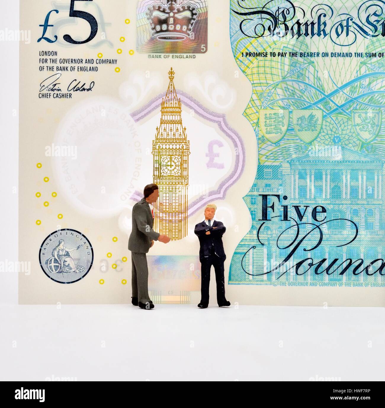 Les hommes d'affaires figurine miniature debout devant une note cinq livres. Banque D'Images