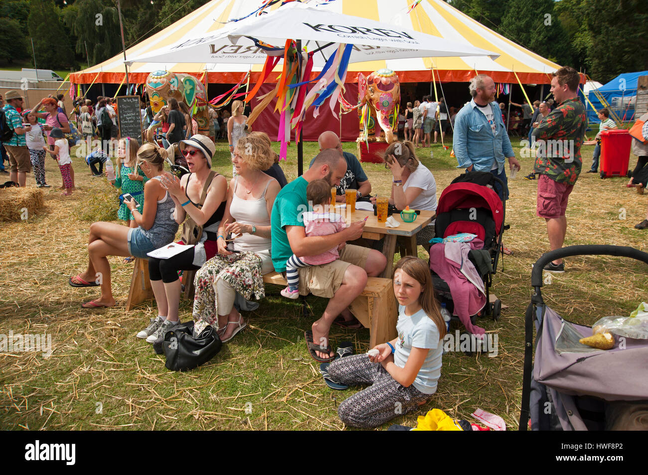 Famille assis à une table sous un parasol appréciant la bière au Festival Port Eliot Cornwall Banque D'Images