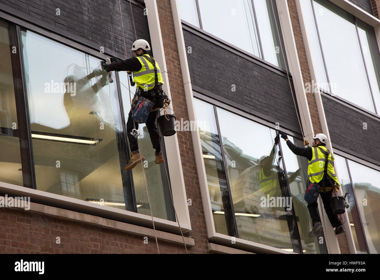 Deux laveurs de vitres à travailler pendant la descente en rappel dans un nouveau bâtiment de bureaux à Londres Banque D'Images