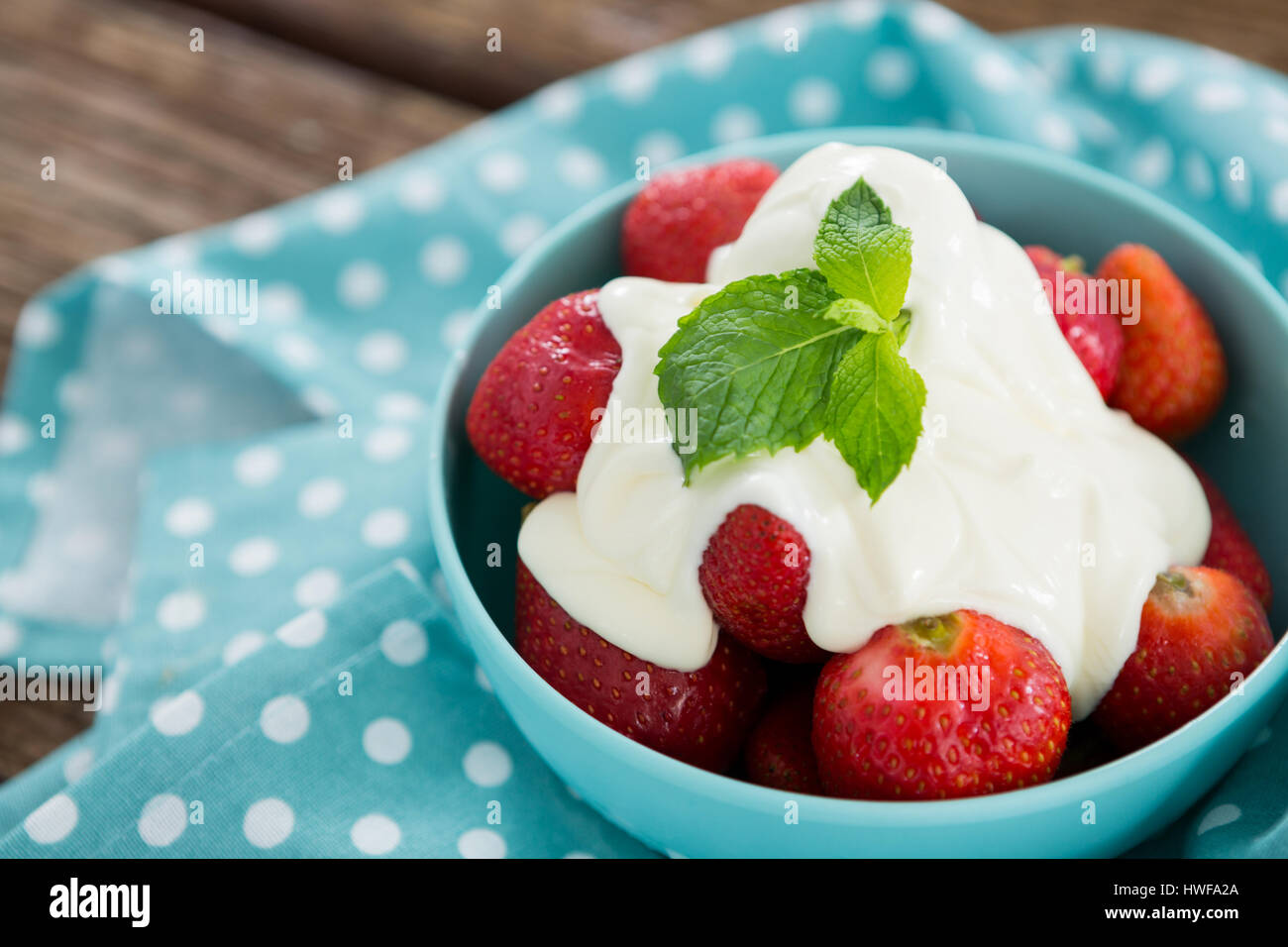 Close-up de fraises fraîches avec de la crème dans un bol sur la table en bois Banque D'Images