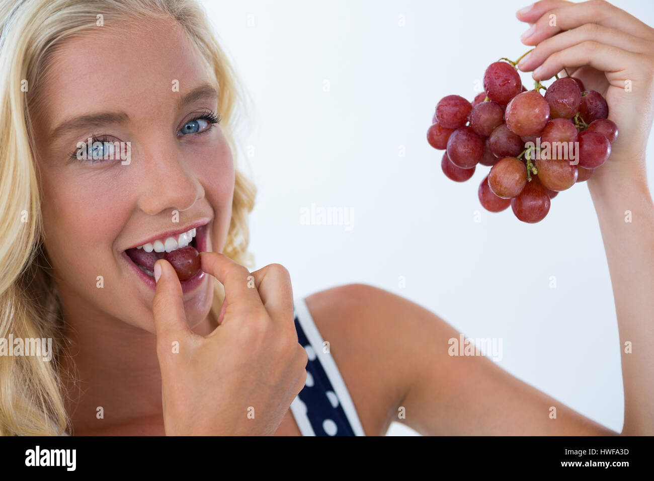 Portrait de femme belle de manger les raisins rouges contre fond blanc Banque D'Images