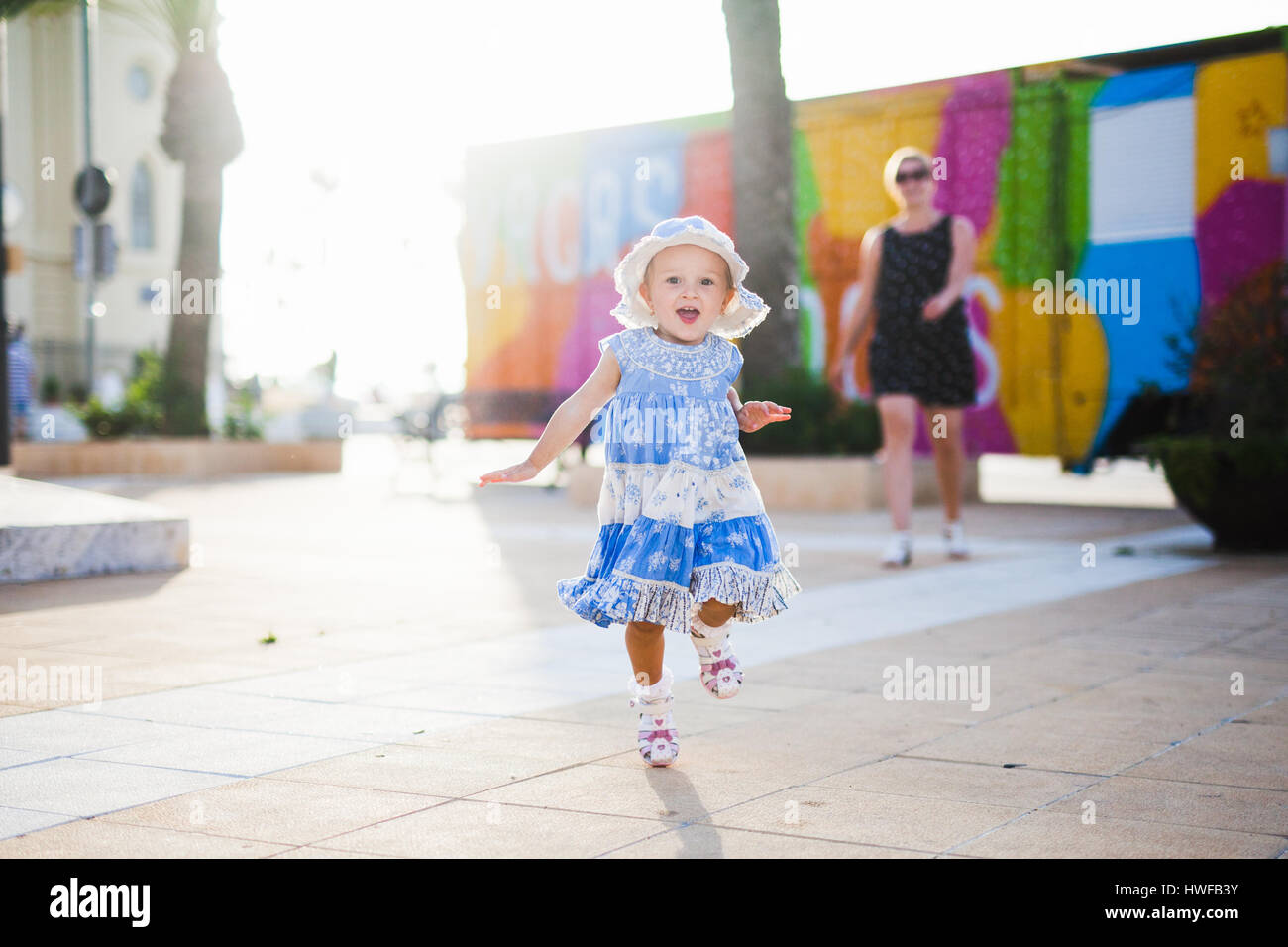 Une petite fille dans une robe bleue et le Panama s'exécute avec joie Banque D'Images