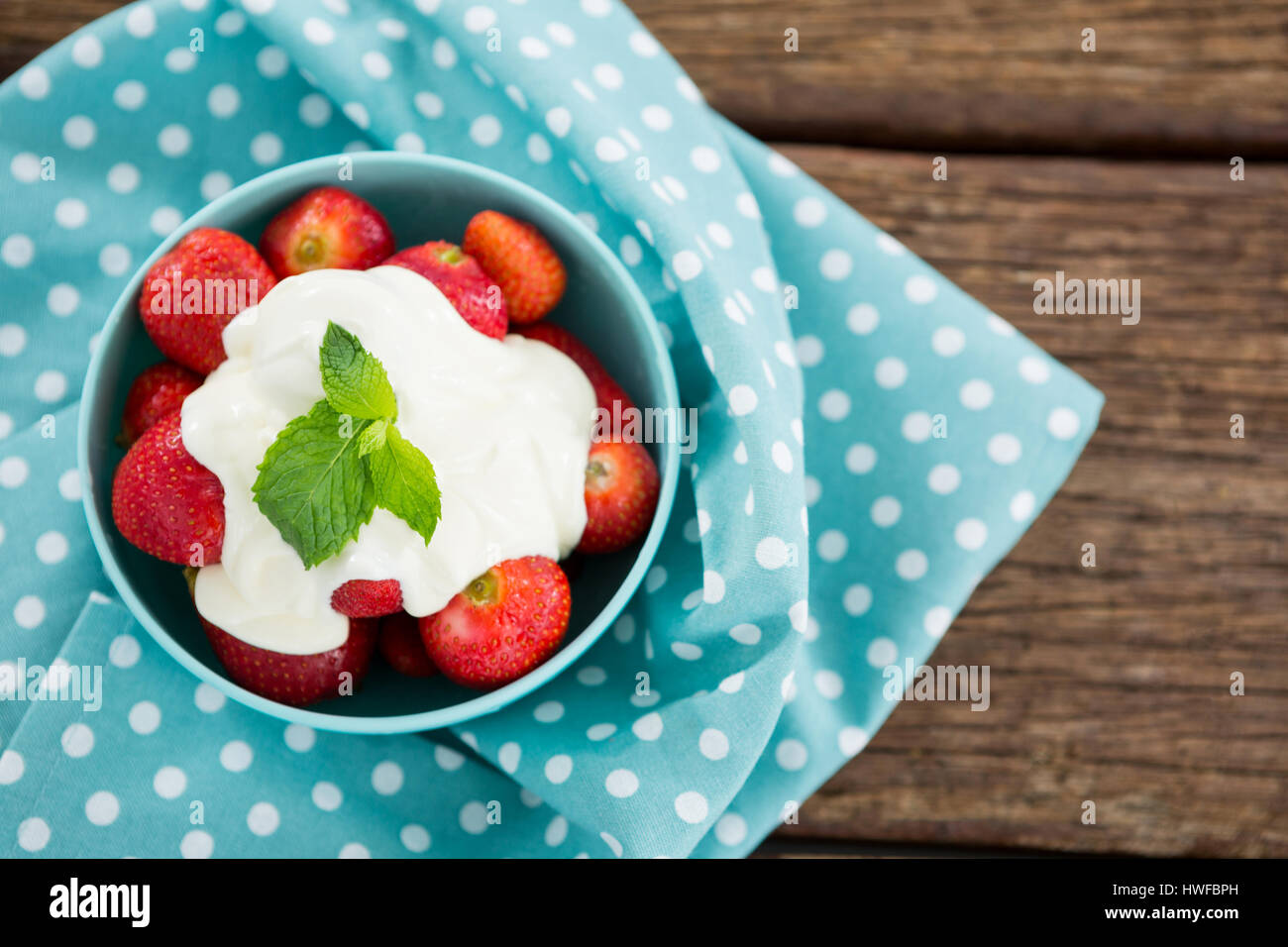 Passage de fraises fraîches avec de la crème dans un bol sur la table en bois Banque D'Images