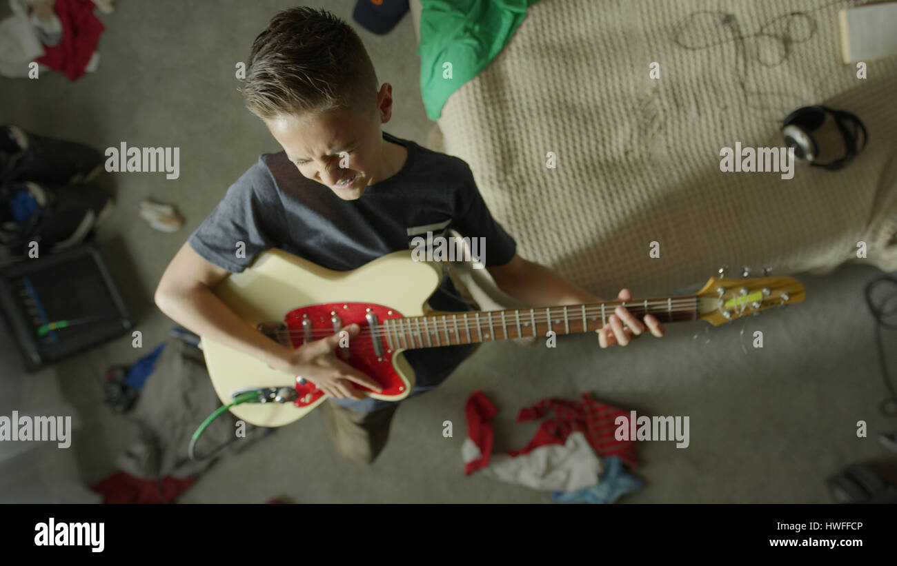 Portrait d'intense teenage boy playing electric guitar dans une chambre en désordre Banque D'Images