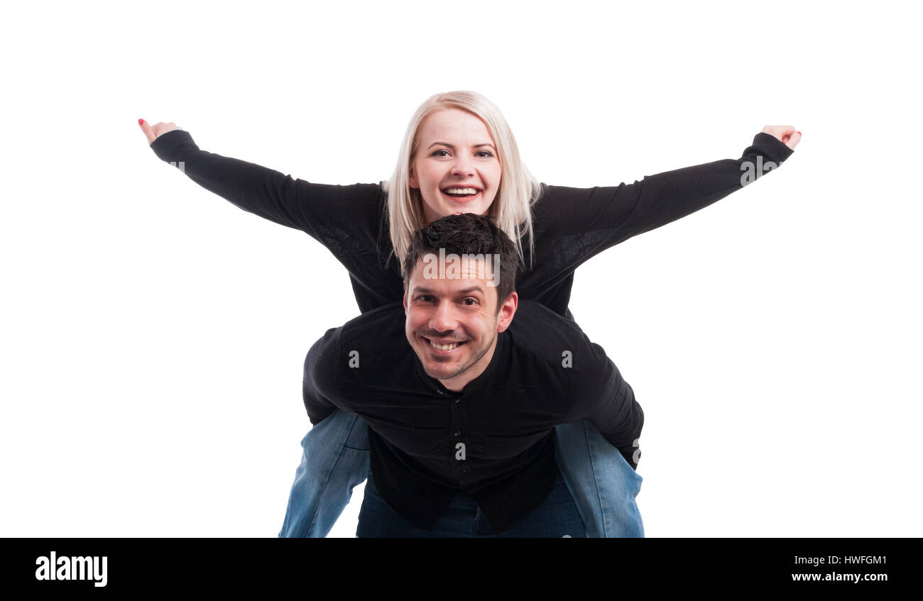 Young man giving piggyback ride à la femme qui se tient avec les bras tendus sur fond blanc Banque D'Images