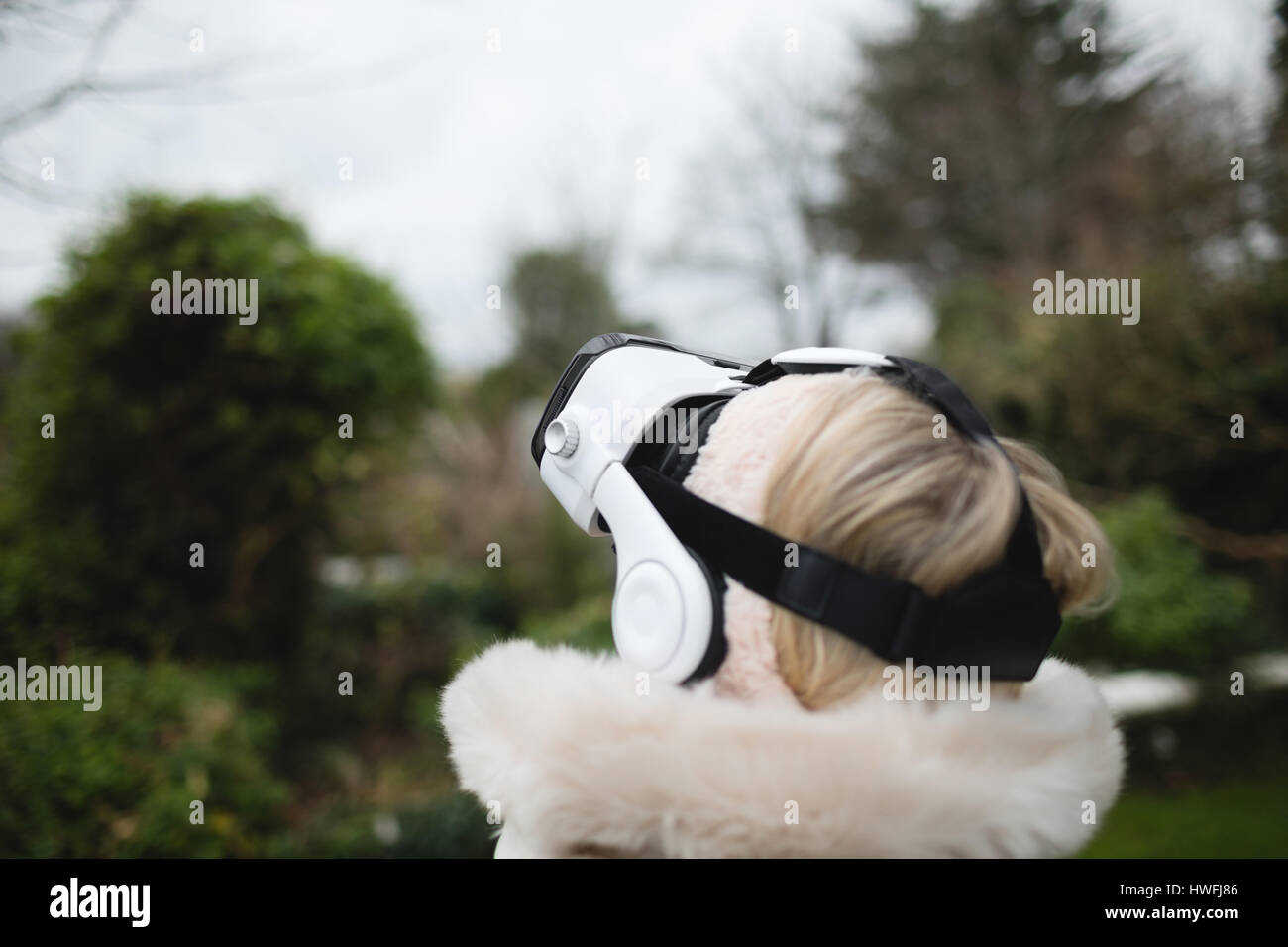 Manteau femme en fureur à l'aide de casque de réalité virtuelle à l'extérieur Banque D'Images Manteau femme en fureur à l'aide de casque de réalité virtuelle à l'extérieur Banque D'Images