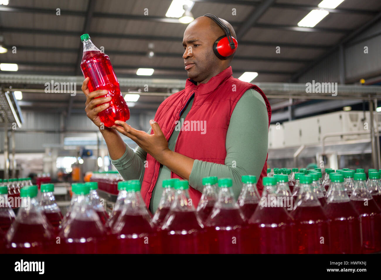 Travailleur homme sérieux portant des earwear bouteille pendant l'inspection en usine Banque D'Images