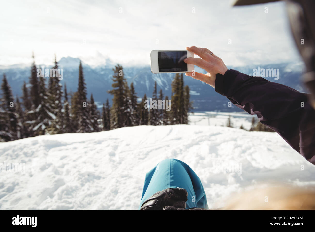 Portrait de personne à photographier la montagne couverte de neige contre des arbres Banque D'Images