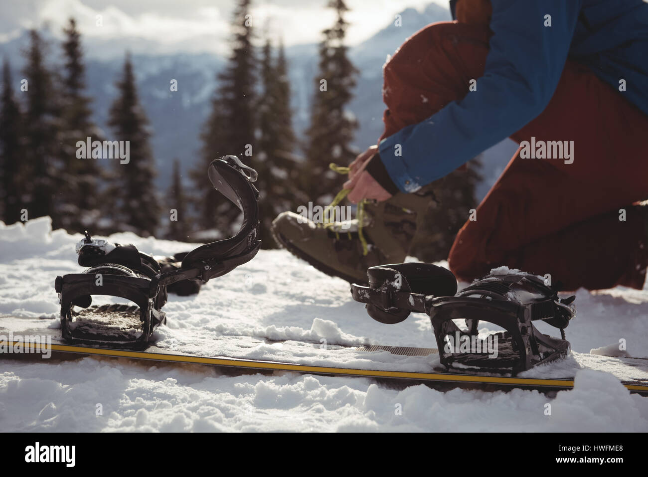 La section basse de femme portant ses chaussures par la planche à neige en hiver montagne Banque D'Images