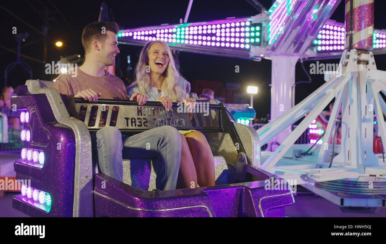 Low angle view of happy laughing couple sitting on amusement park ride fête foraine Banque D'Images