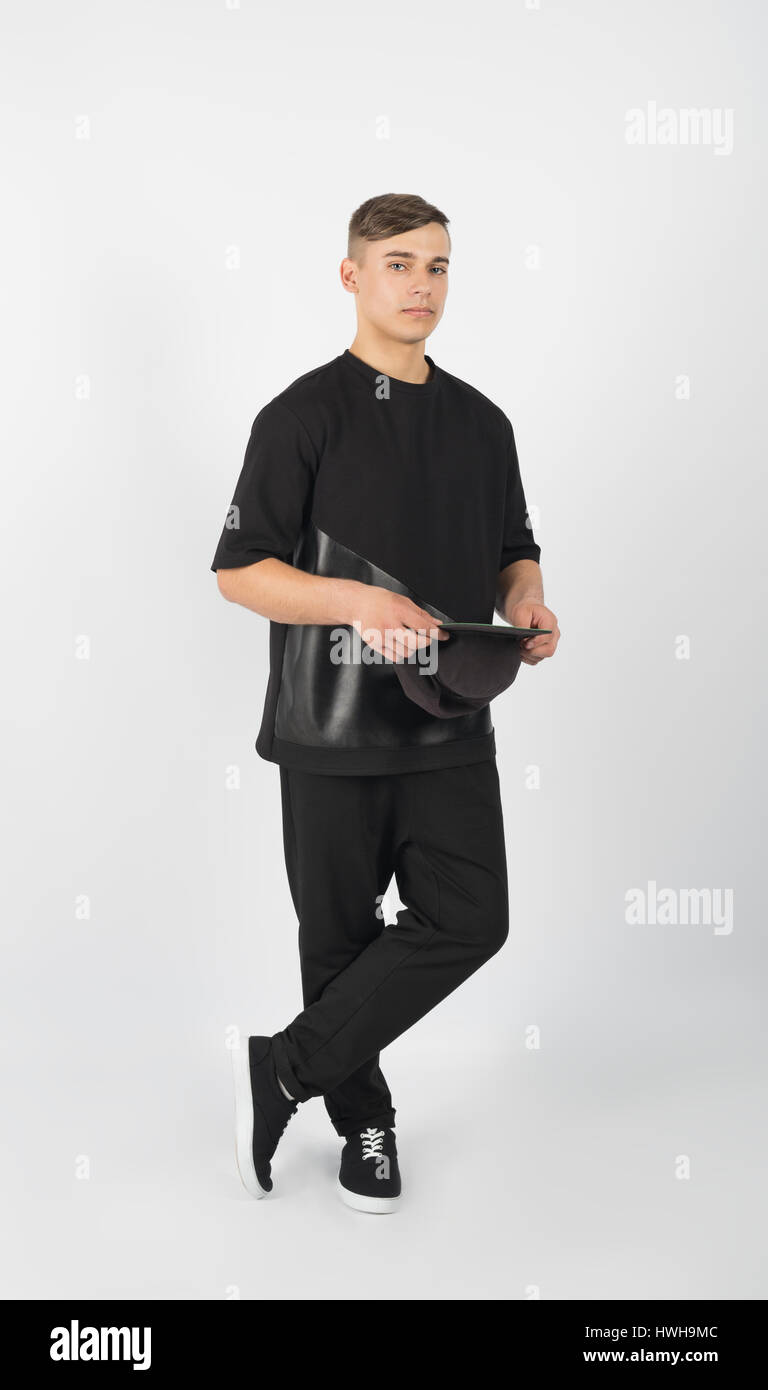 La jeune homme portant des vêtements noirs et sneakers snapback holding isolé sur fond blanc Banque D'Images