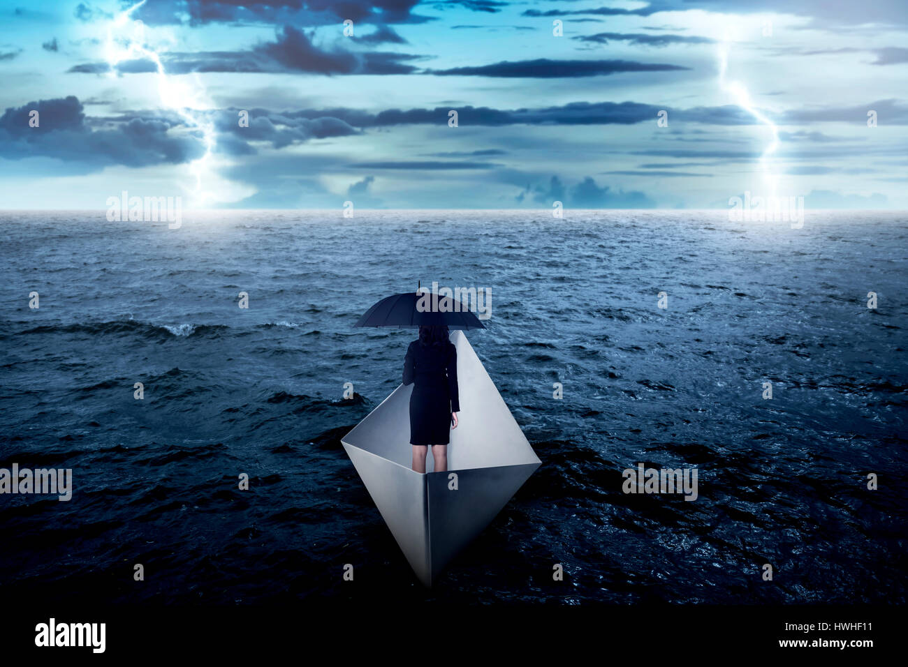 Asian business woman holding umbrella seul sur la mer, de la voile avec bateau de papier. Conceptuel du risque d'entreprise Banque D'Images