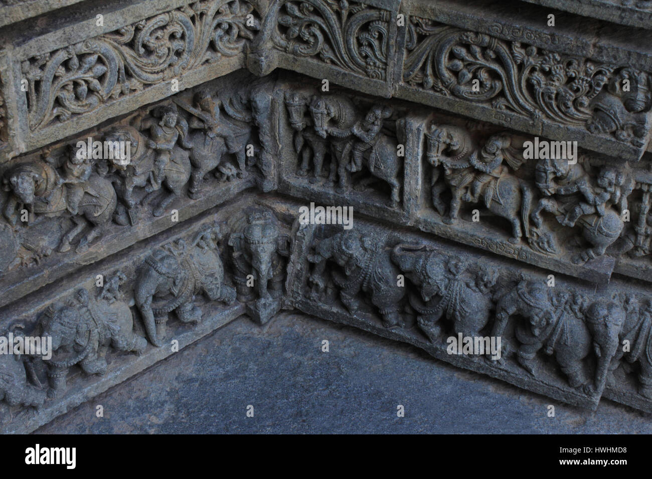 Close up de sculptures sur pierre de feuillage, des guerriers , cavaliers, procession d'éléphants où deux murs d'angle se rencontrent sur le lieu de culte mur à Chennakesa Banque D'Images