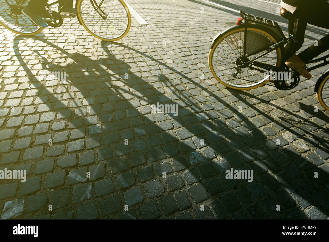 Les cyclistes de la ville, les gens la bicyclette sur les routes pavées, l'ombre de la personne sur le vélo Banque D'Images