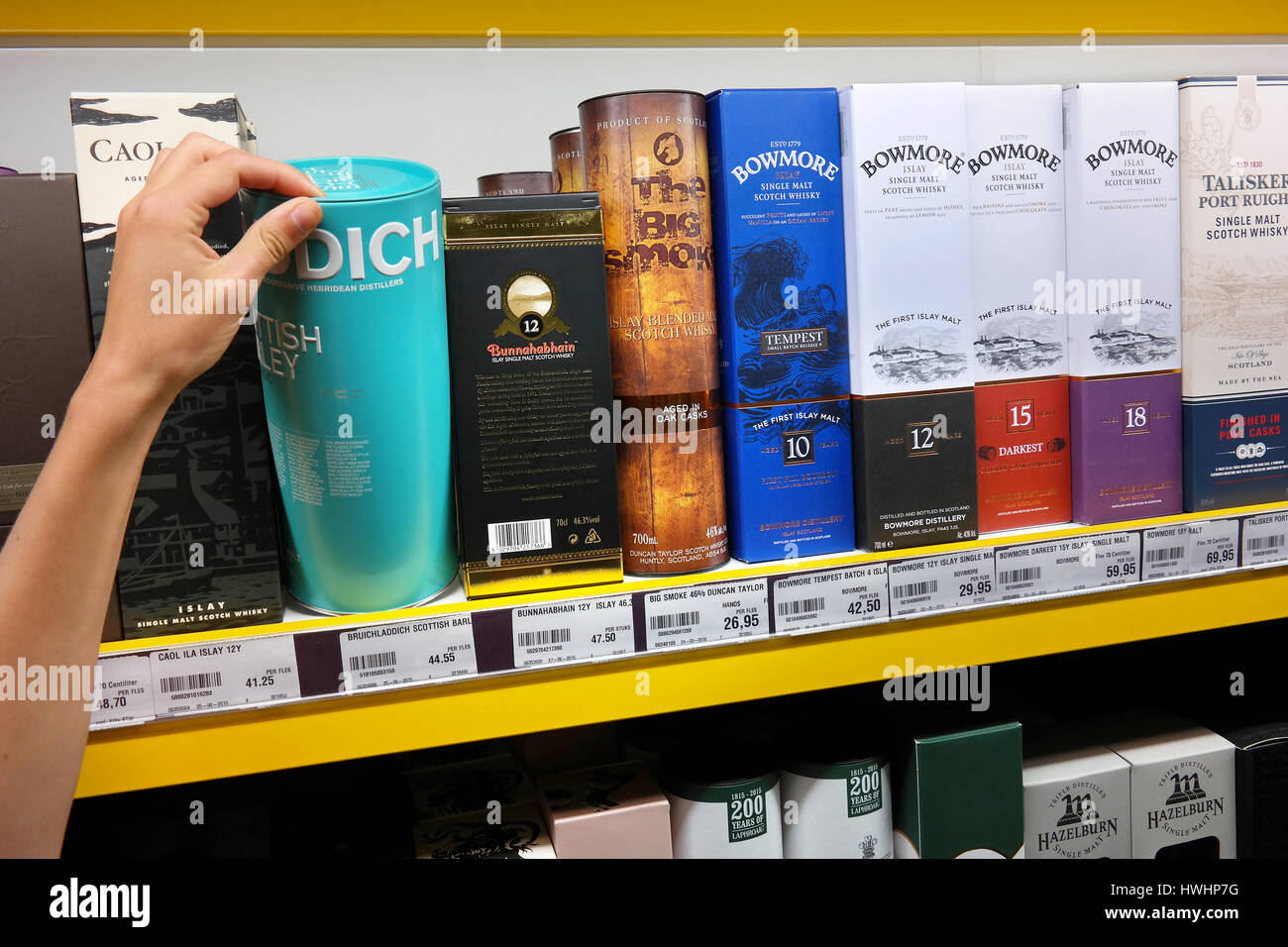 Un client choisit une boîte avec une bouteille de whisky dans un magasin. Banque D'Images