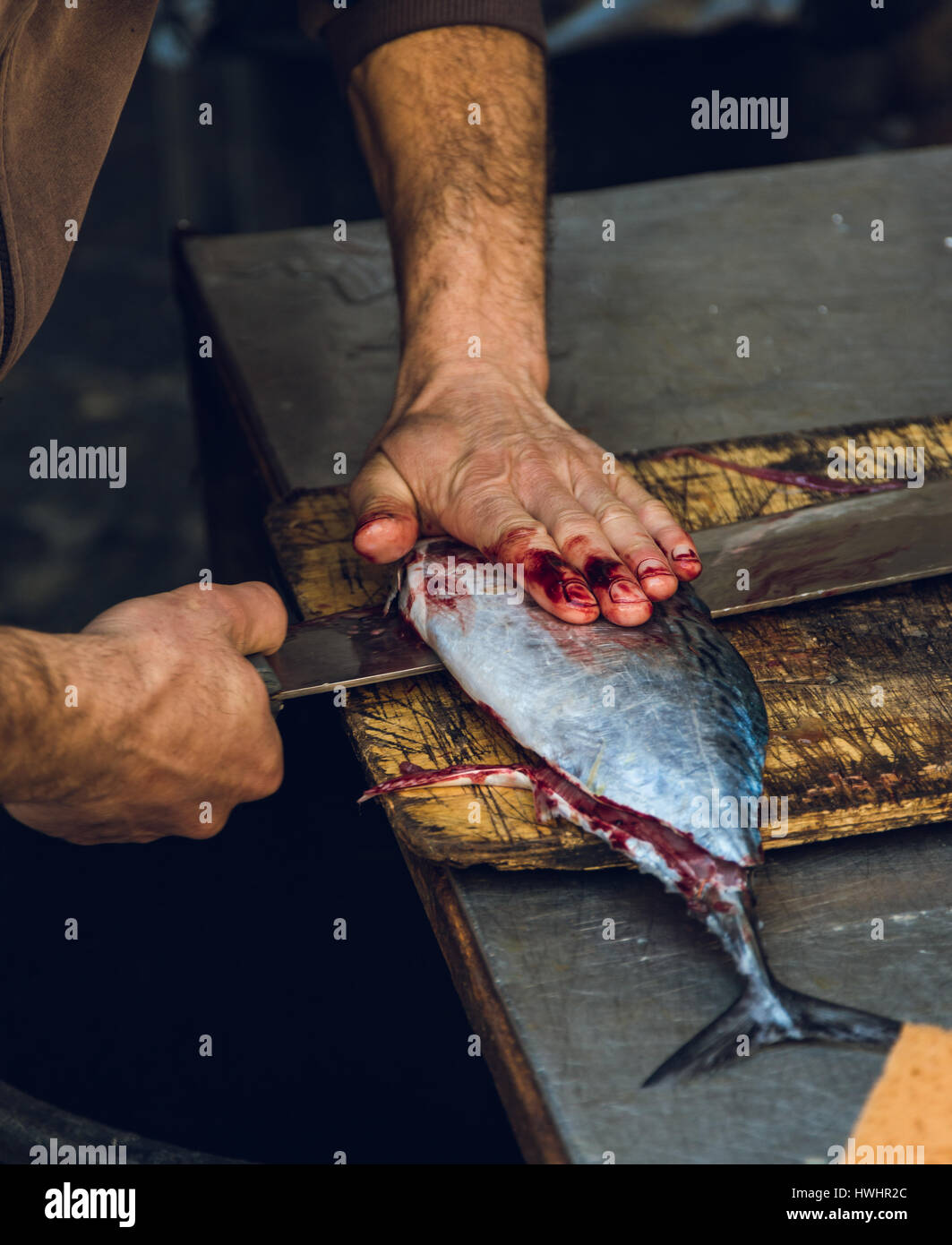 Poissonnier couper un petit thon sur une planche à découper en bois, marché aux poissons Catane, Italie Banque D'Images