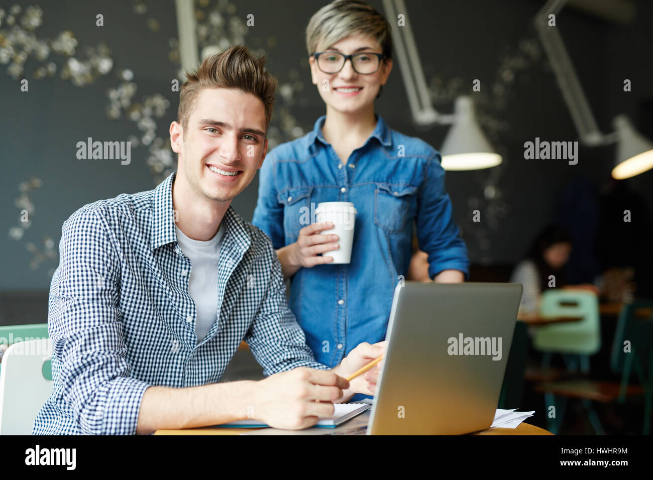 Groupe de jeunes designers joyeuse qui pose pour la photographie dans un petit café tout en ayant réunion informelle, portrait en taille Banque D'Images