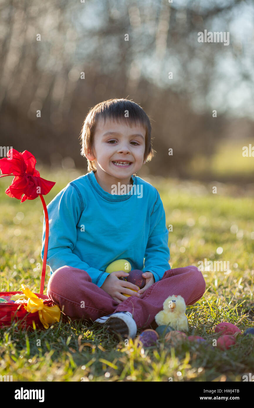 Adorable garçon dans le parc, s'amusant avec les oeufs colorés pour Pâques, printemps Banque D'Images