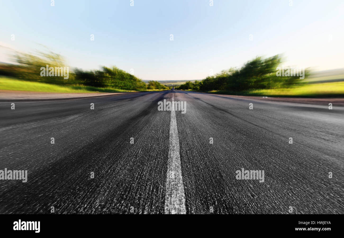 La route d'asphalte à travers le champ vert dans la journée d'été Banque D'Images