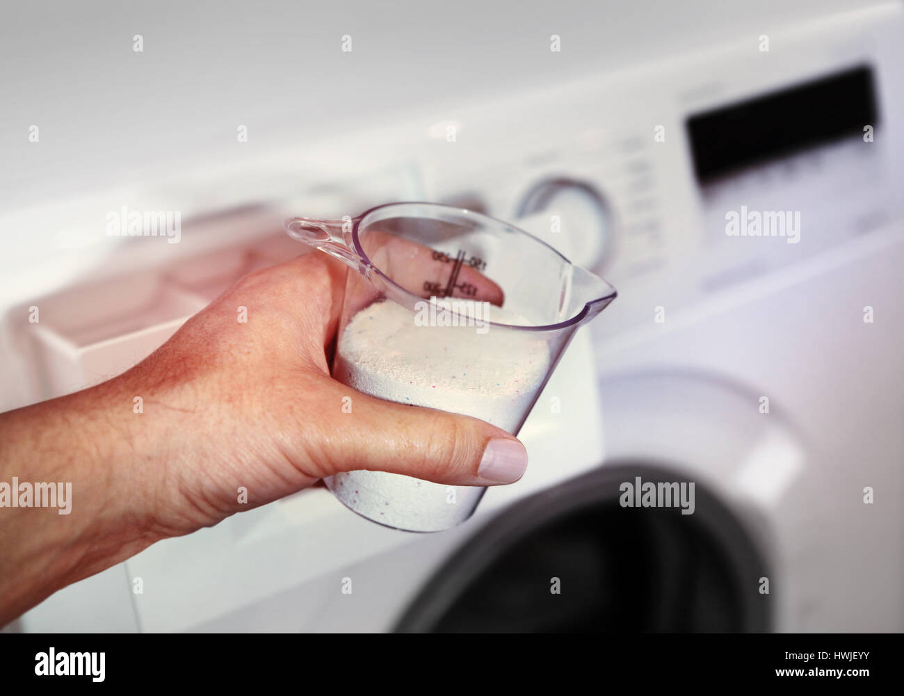 Main de femme qui remplit de détergent dans la machine à laver Banque D'Images