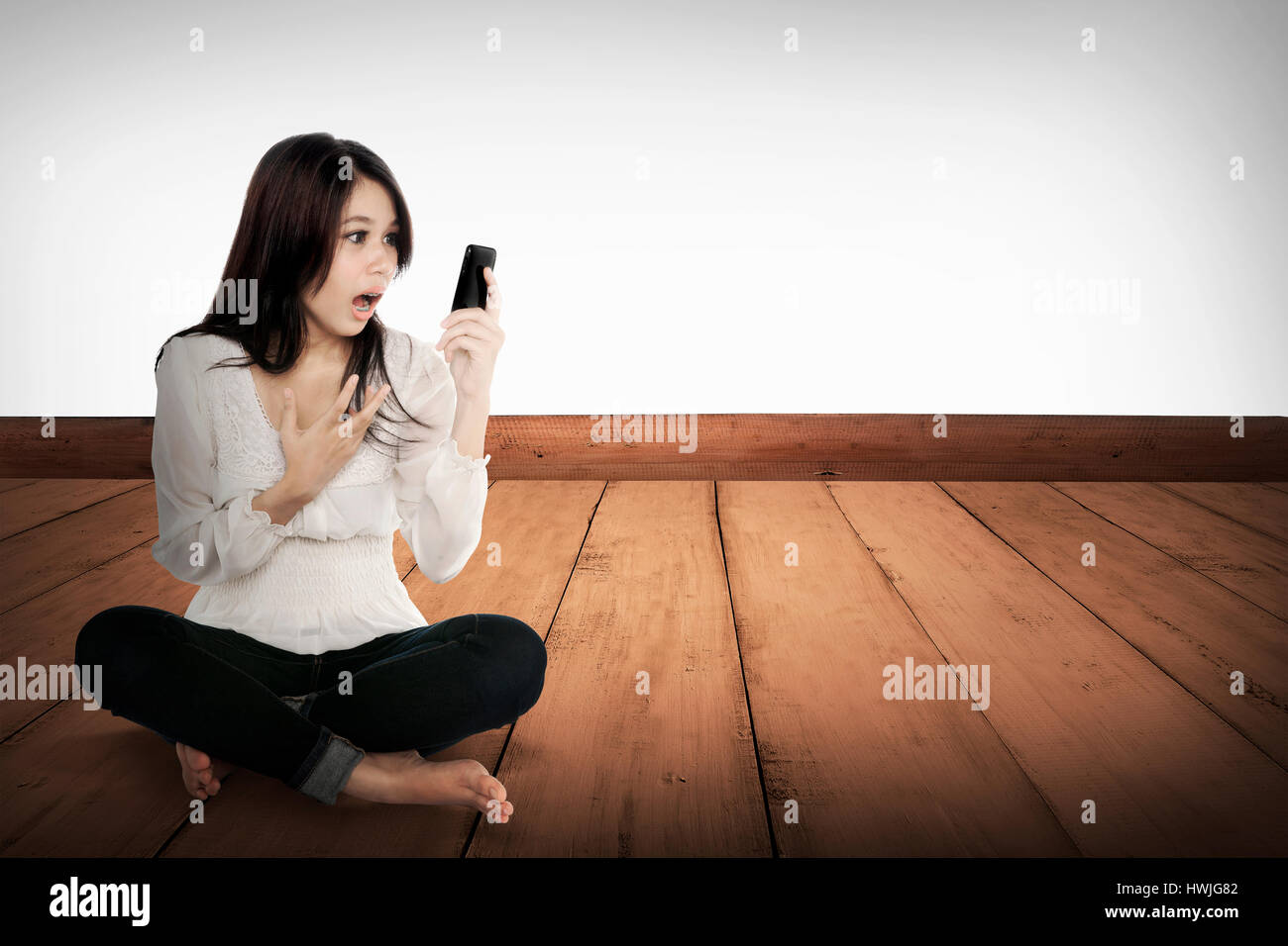 Pretty asian girl using cellphone sur le plancher en bois. concept de télécommunications Banque D'Images