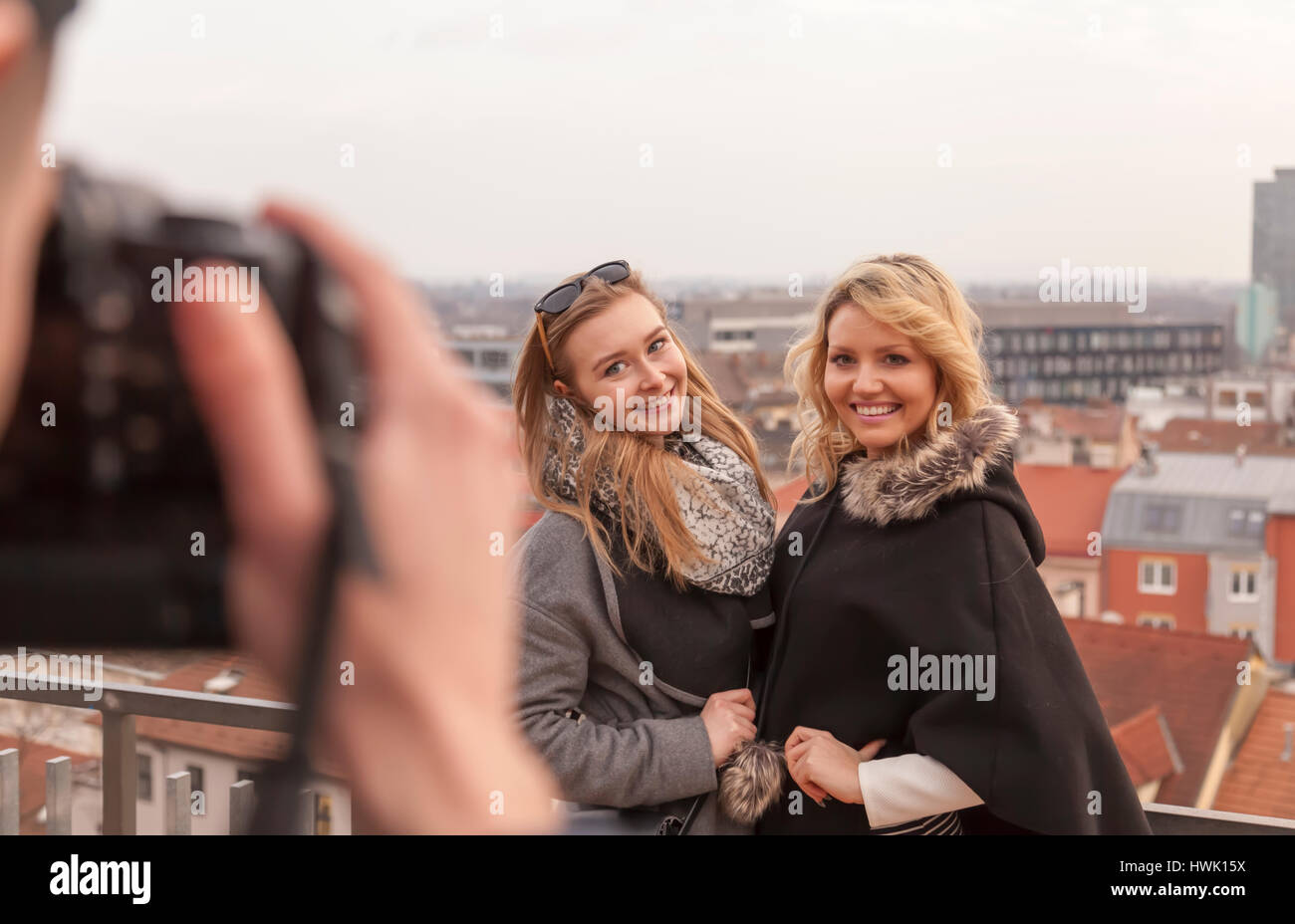Photographe prend des photos de deux femmes en face de city scape. Les deux modèles sont smiling at man taking pictures with cityscape background panorama Banque D'Images
